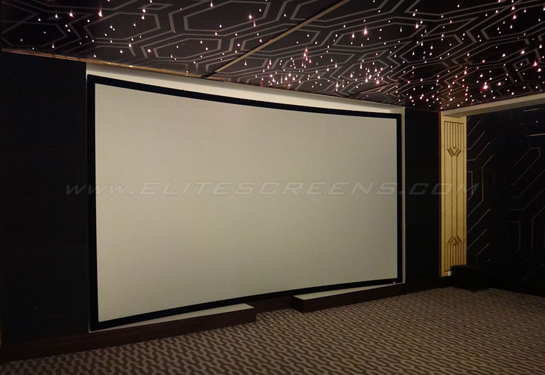 Una sala home theater. Grande schermo di proiezione bianco. Cornice nera. Soffitto scuro con luci.