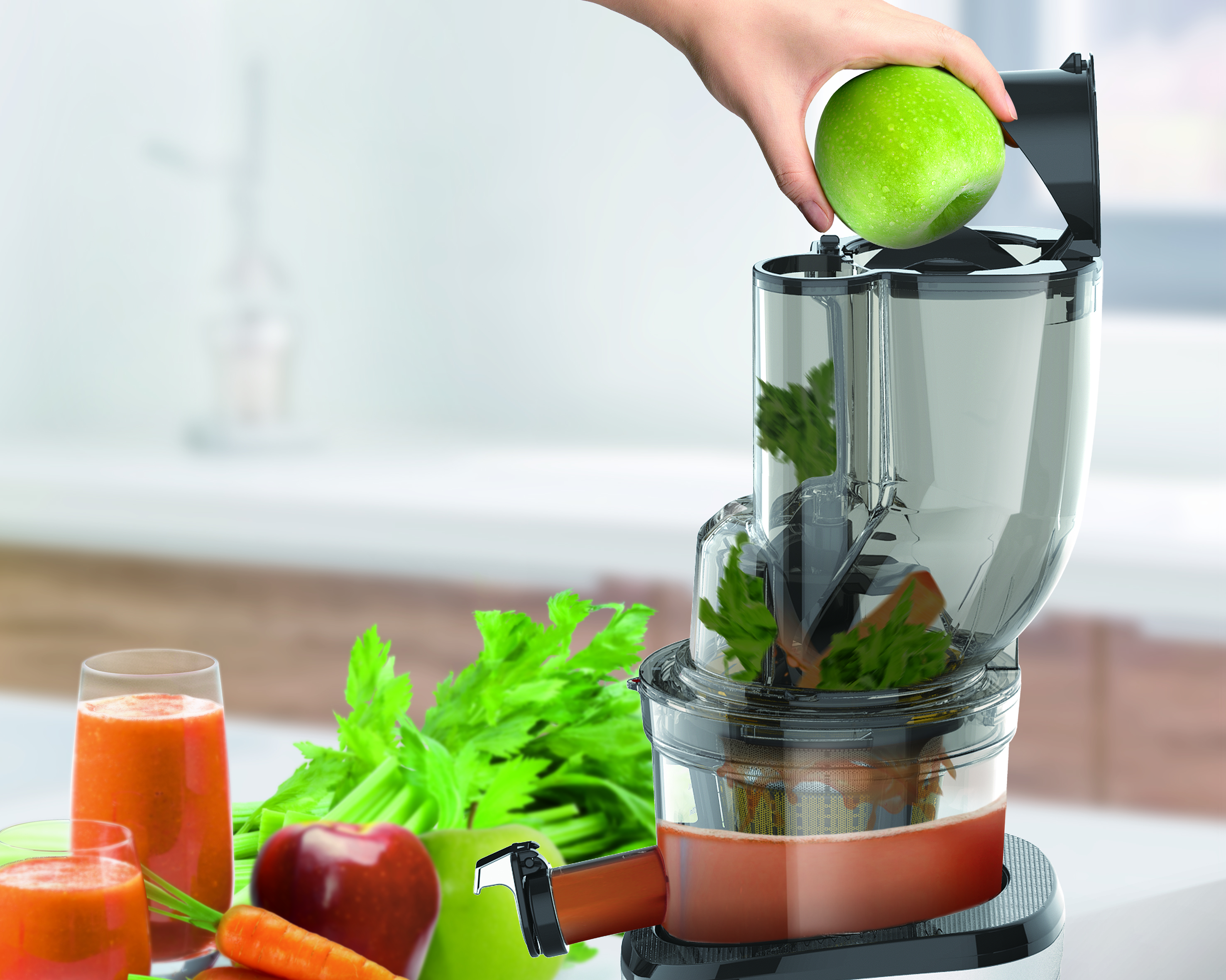 Una mano colocando una manzana verde en una exprimidora con otras frutas y jugo.