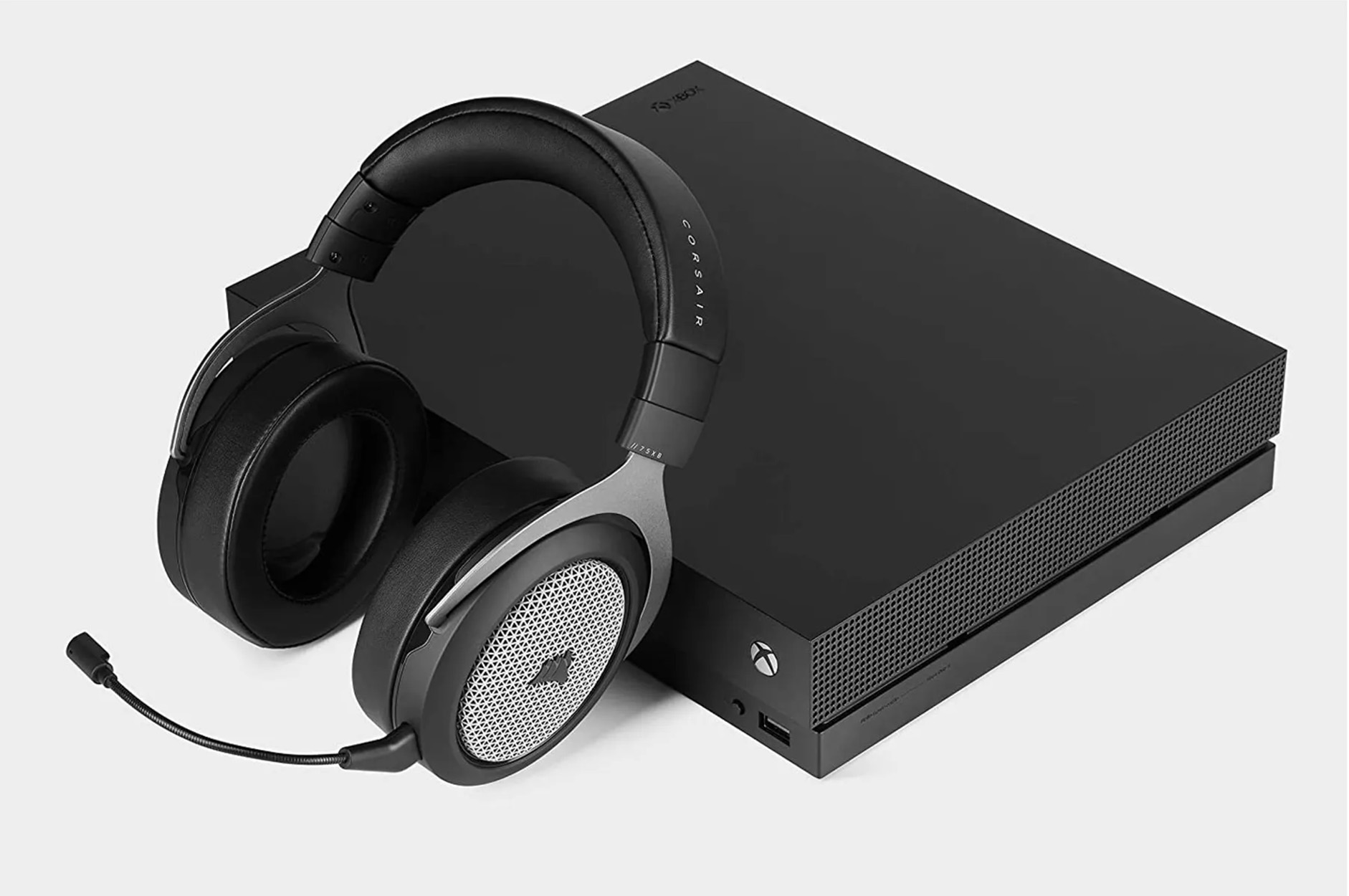 Consola Xbox negra con auriculares Corsair negros. El auricular está a la izquierda de la consola.