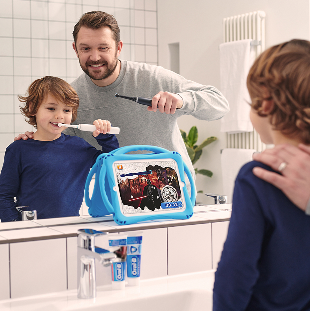 Padre e figlio che si lavano i denti con un tablet che mostra un gioco di Star Wars nello specchio.
