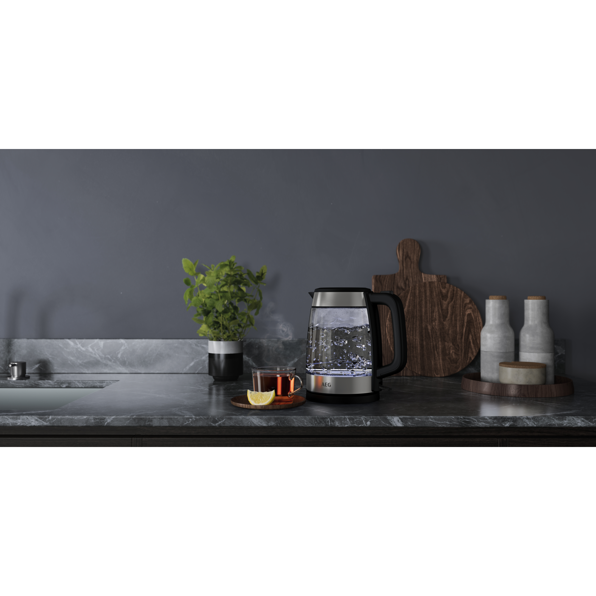 Wasserkocher mit Dampf, Teetasse und weitere Gegenstände auf der Arbeitsplatte.