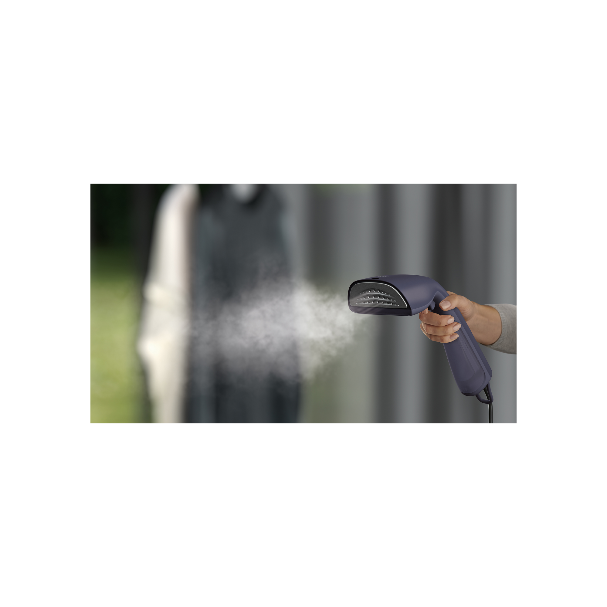 Hand hält einen Kleidungsdampfer. Dampf wird freigesetzt. Dunkler Hintergrund.