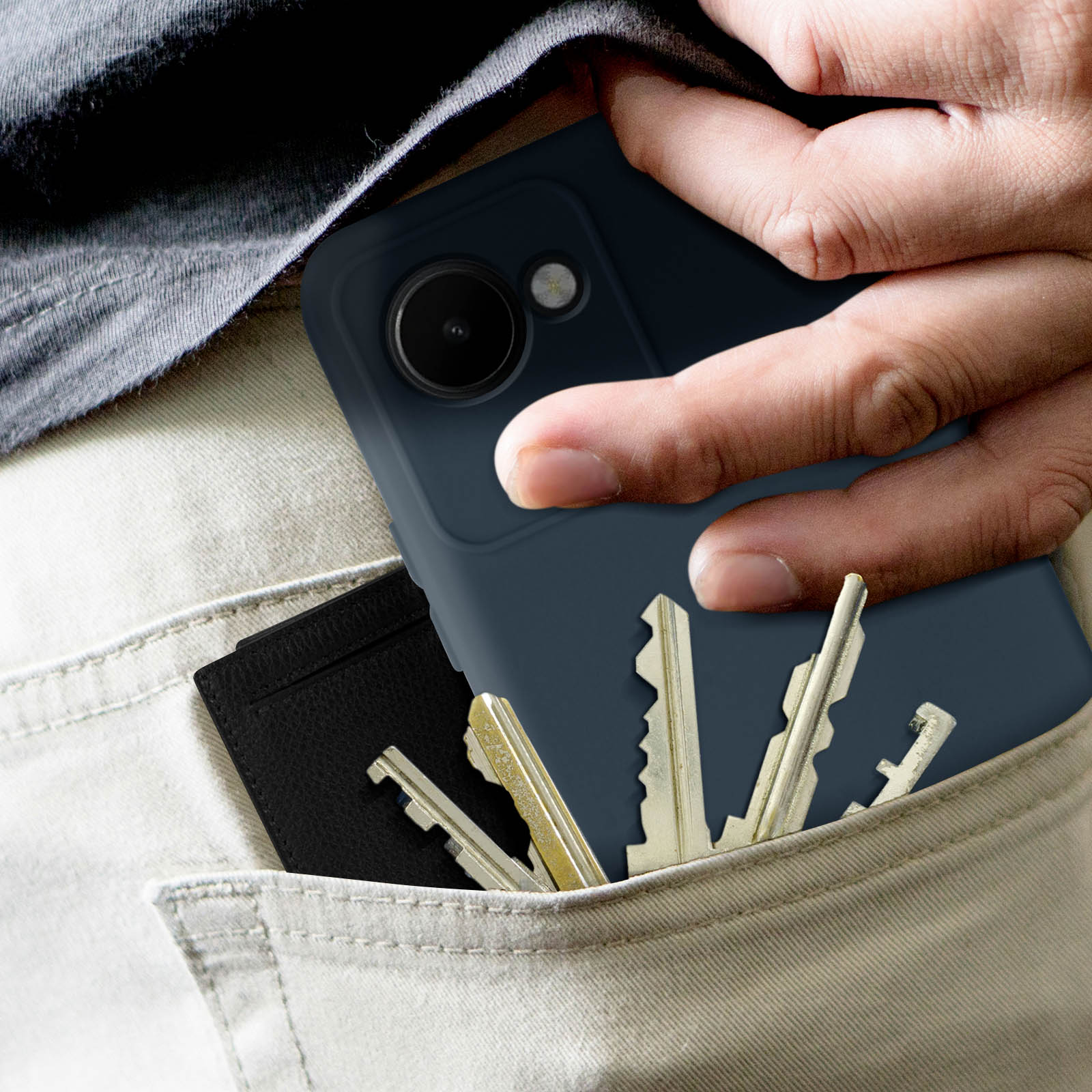 Eine Hand hält ein dunkelblaues Telefon in einer Tasche mit Schlüsseln und einer Geldbörse.