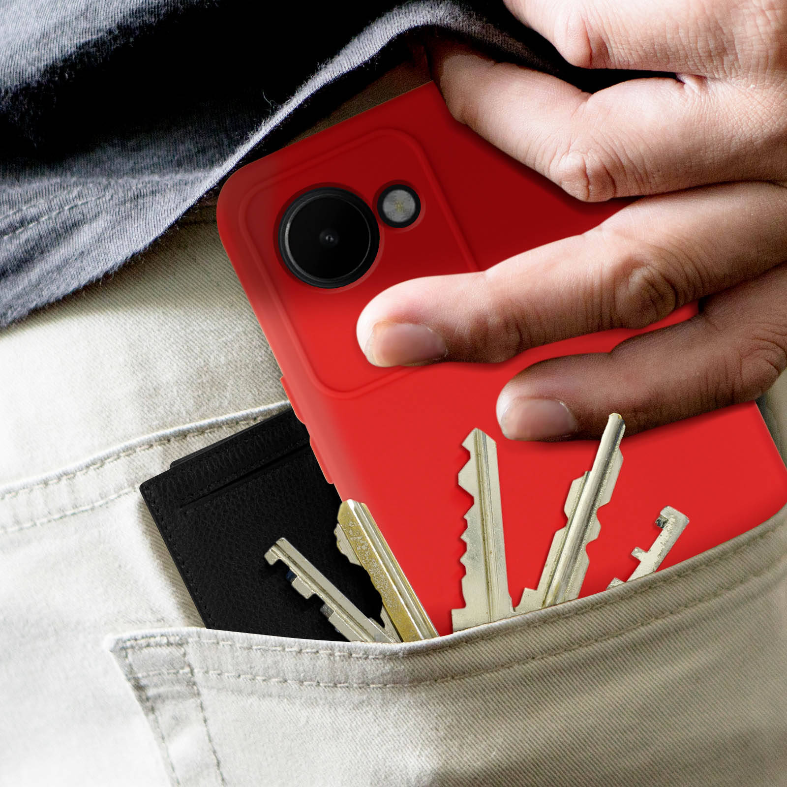 Hand in einer Tasche mit roter Handyhülle, Schlüsseln und einem schwarzen Kartenhalter sichtbar.