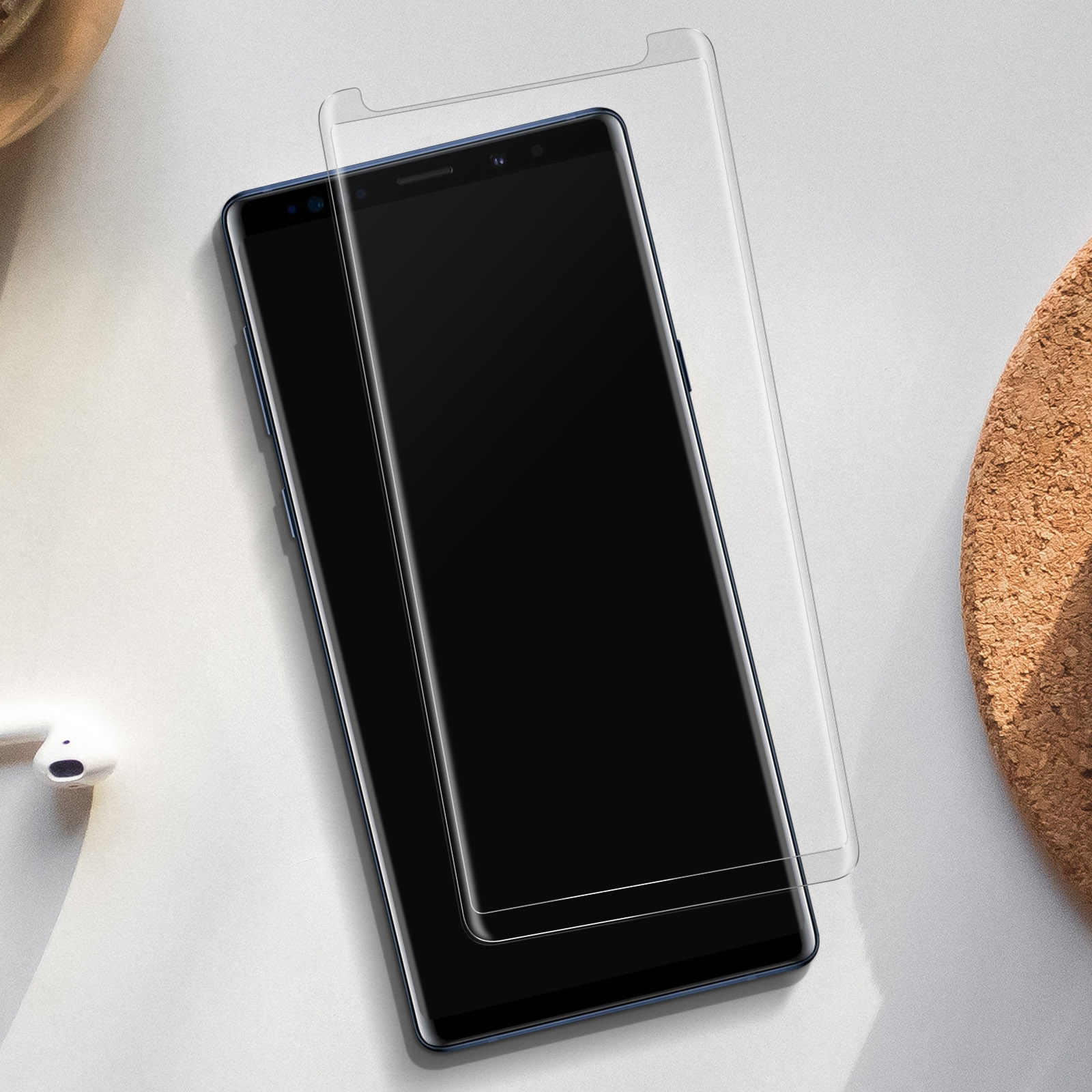 Un téléphone avec un protecteur d'écran appliqué. Le téléphone est noir avec un bord bleu. Surface blanche avec des écouteurs.
