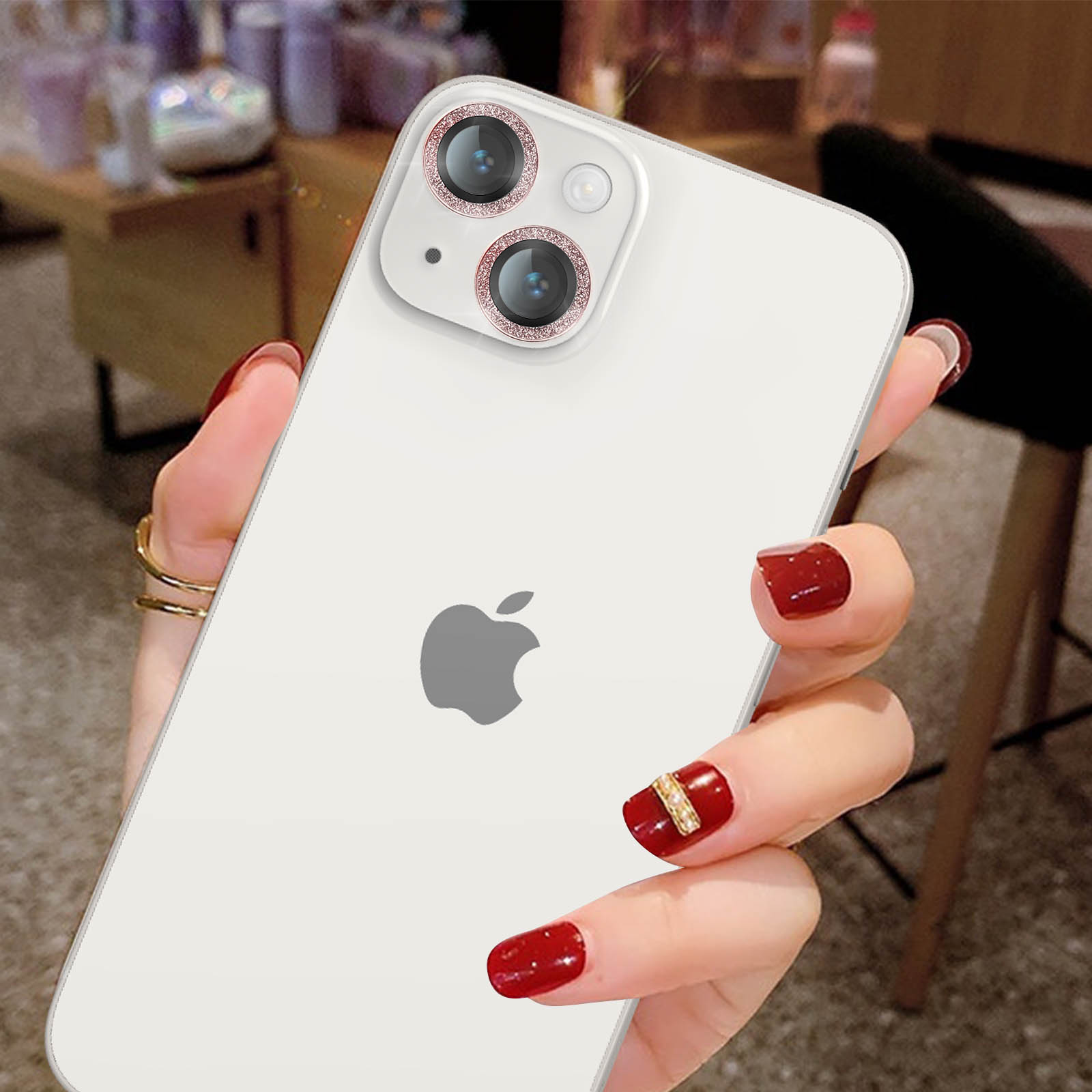 Hand einer Frau, die ein weißes Telefon mit Kameralinsen hält, rote Nägel.