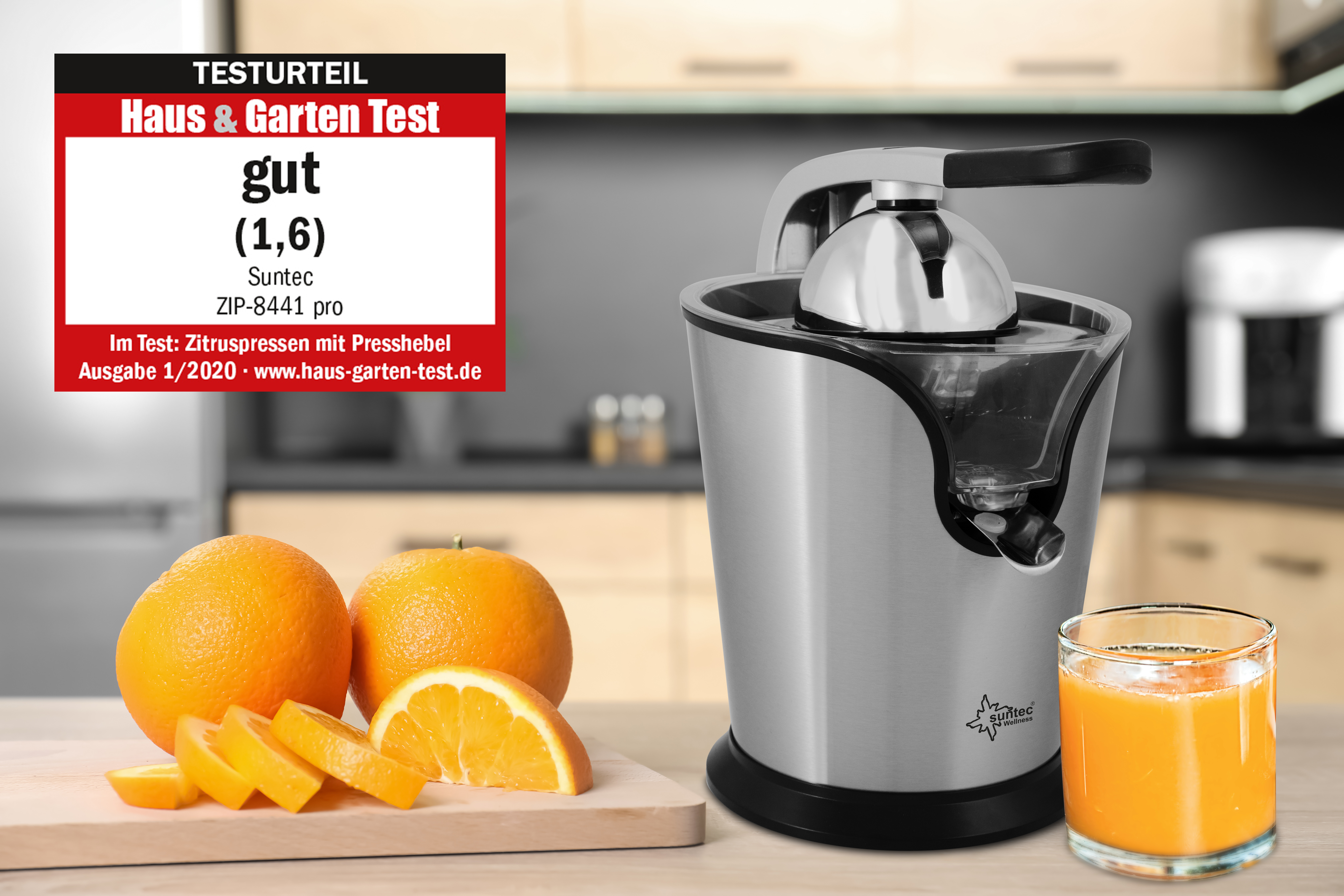 Ein silberner und schwarzer Entsafter mit Orangen und Saft. Ein Testaufkleber sagt "Gut".