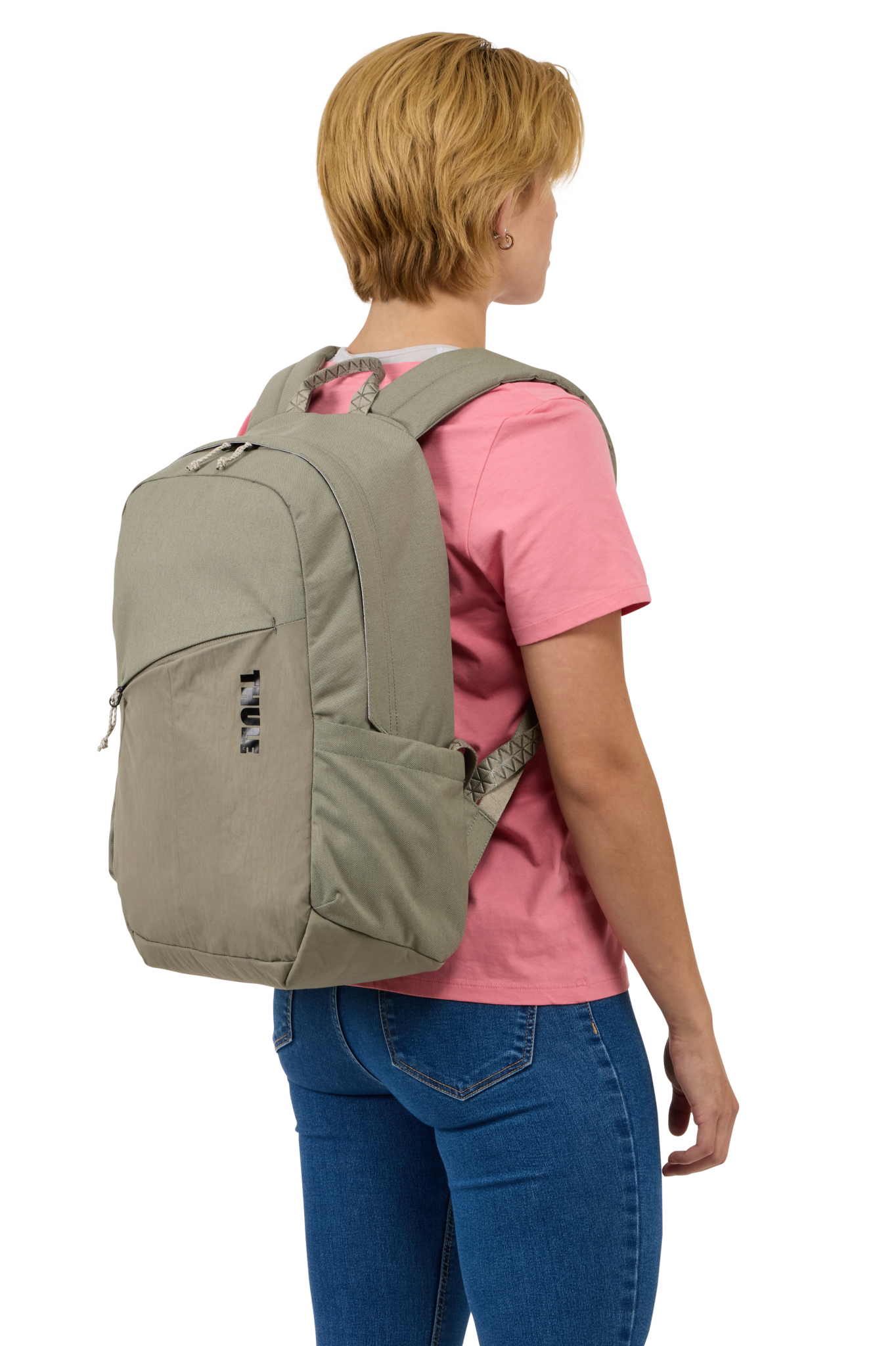 Frau mit Thule-Rucksack. Grauer und schwarzer Rucksack, rosa Hemd, blaue Jeans.