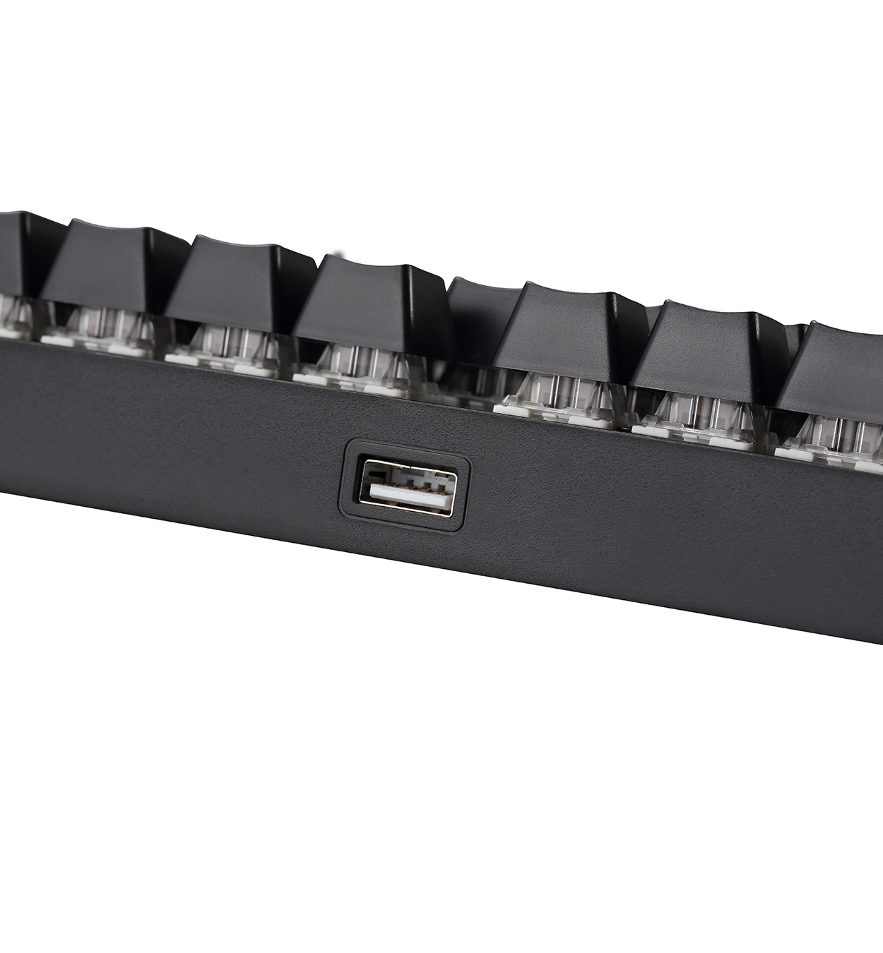 Primer plano del lateral de un teclado negro con un puerto USB. El teclado está sobre un fondo blanco.