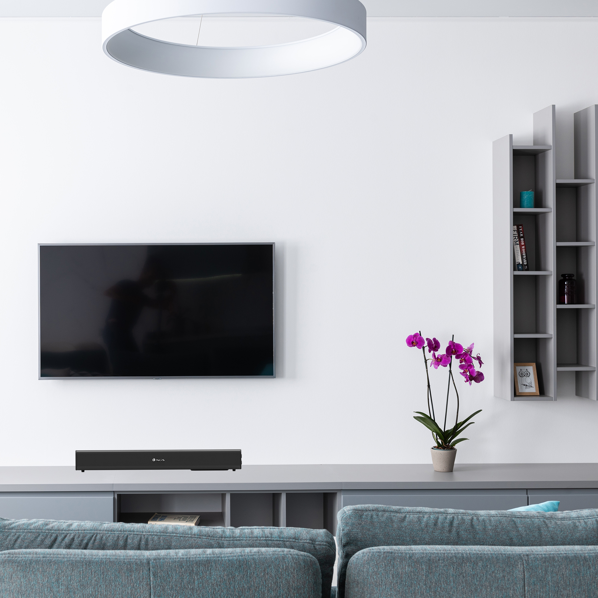 Wohnzimmer mit Fernseher, Soundbar und Orchidee. Grau- und Blautöne.