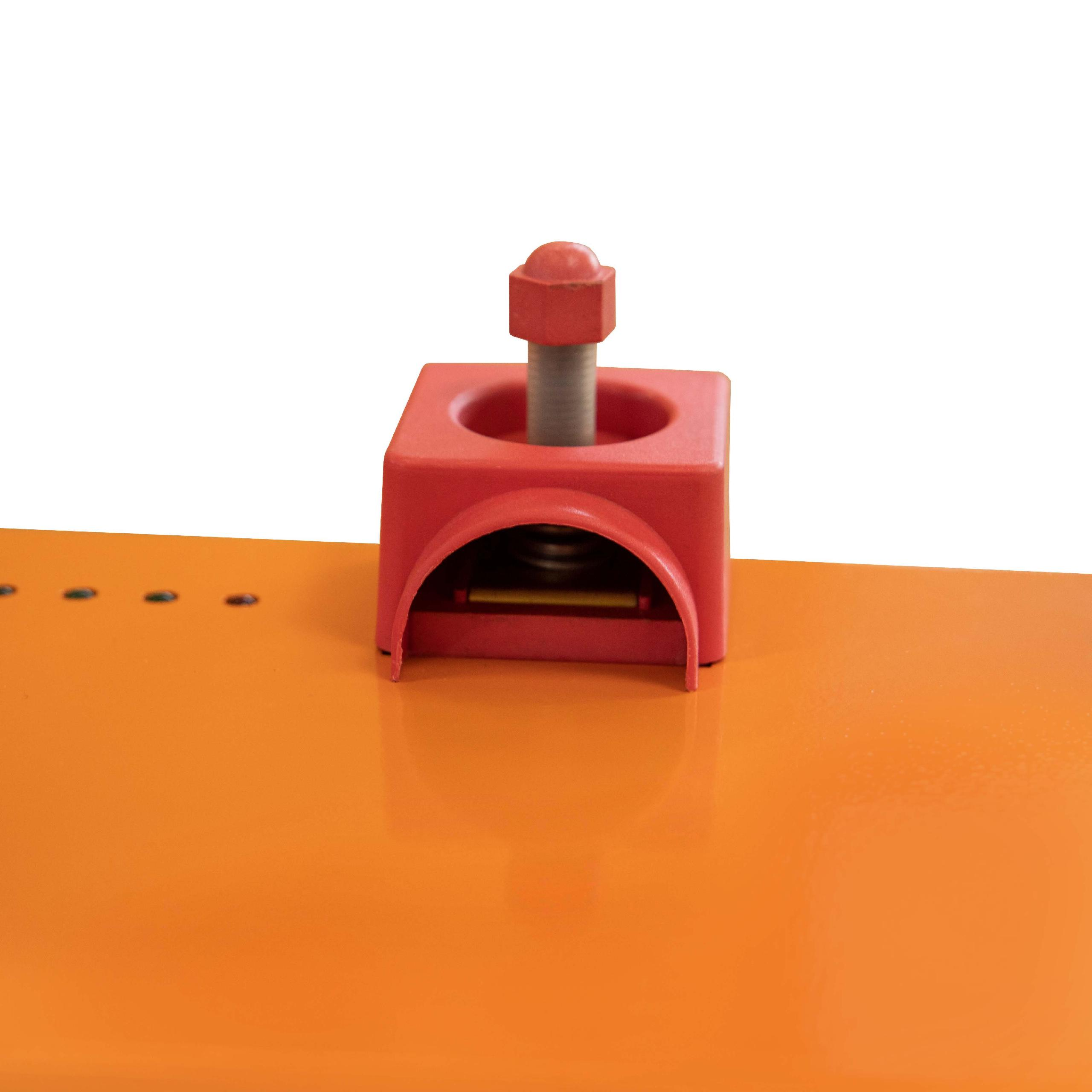 Rotes Metallteil mit Schraube, Mutter und Loch auf orangefarbener Oberfläche.