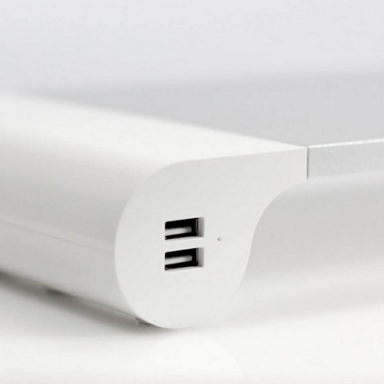 Primer plano de un dispositivo blanco con puertos USB, fondo liso.