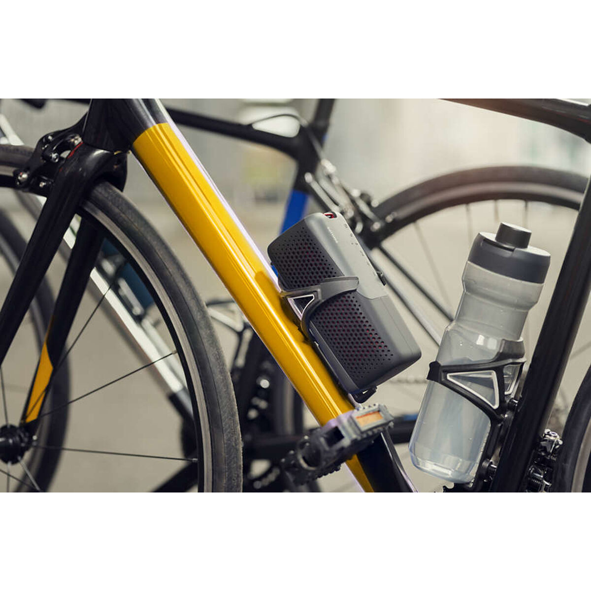 Rower z głośnikiem i butelką z wodą przymocowaną do ramy. Głośnik jest czarny.