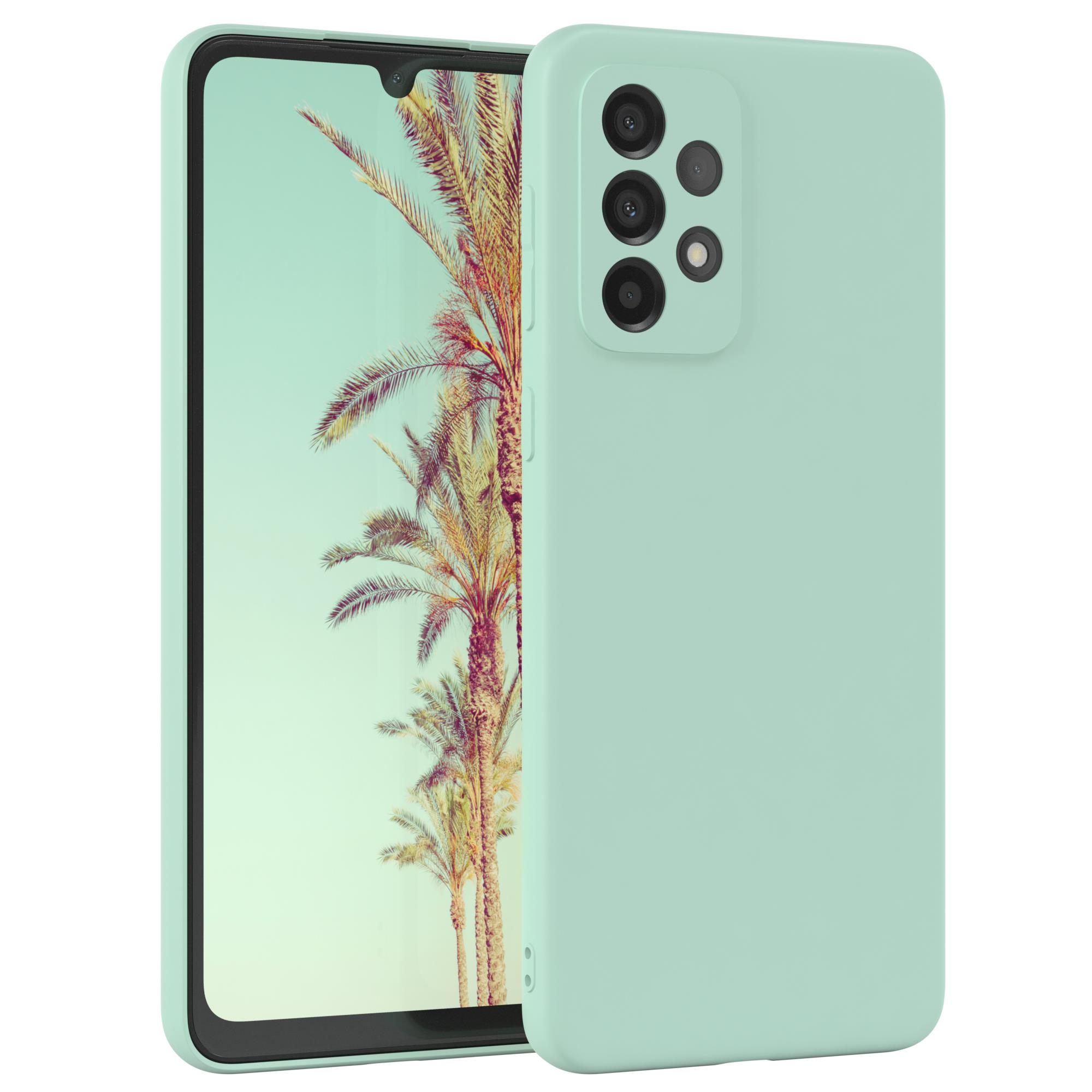 Minzgrüne Handyhülle und ein Telefon mit tropischem Landschaftshintergrund. Das Telefon hat mehrere Kameras.