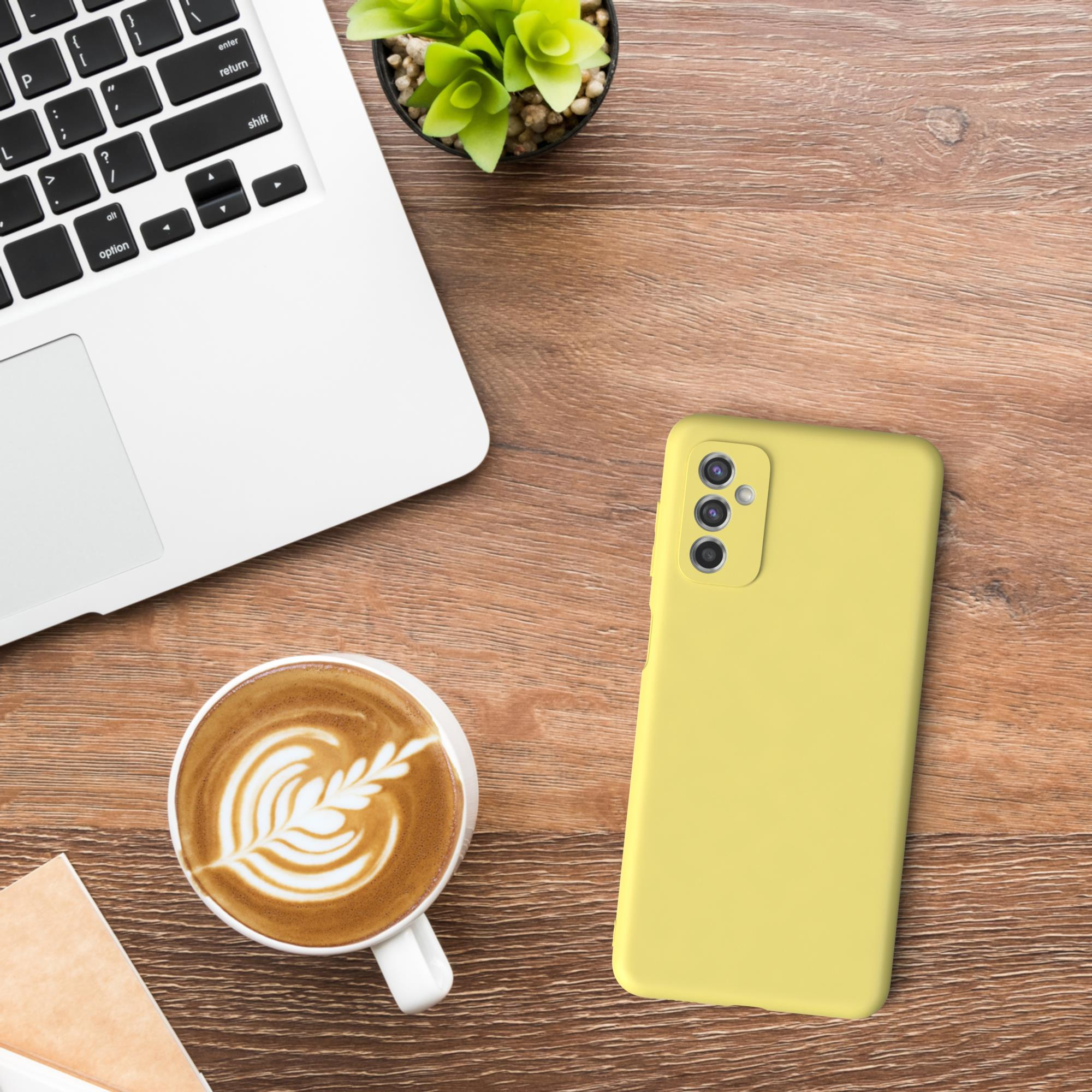 Laptop, Kaffee, Telefon und Pflanze auf einem Holztisch.