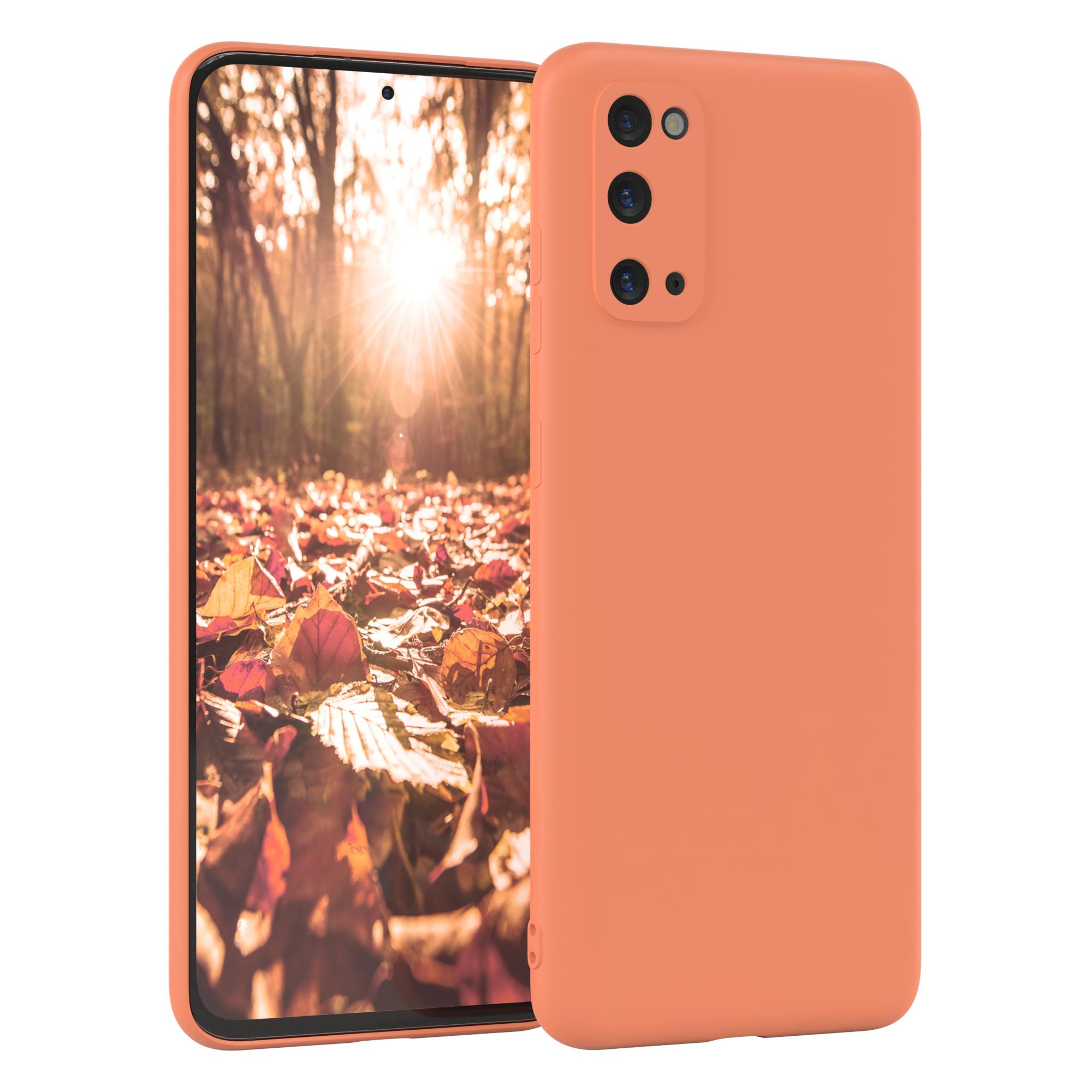 Oranges Telefon in einer Hülle, mit Waldhintergrund. Drei Rückkameras sind sichtbar.