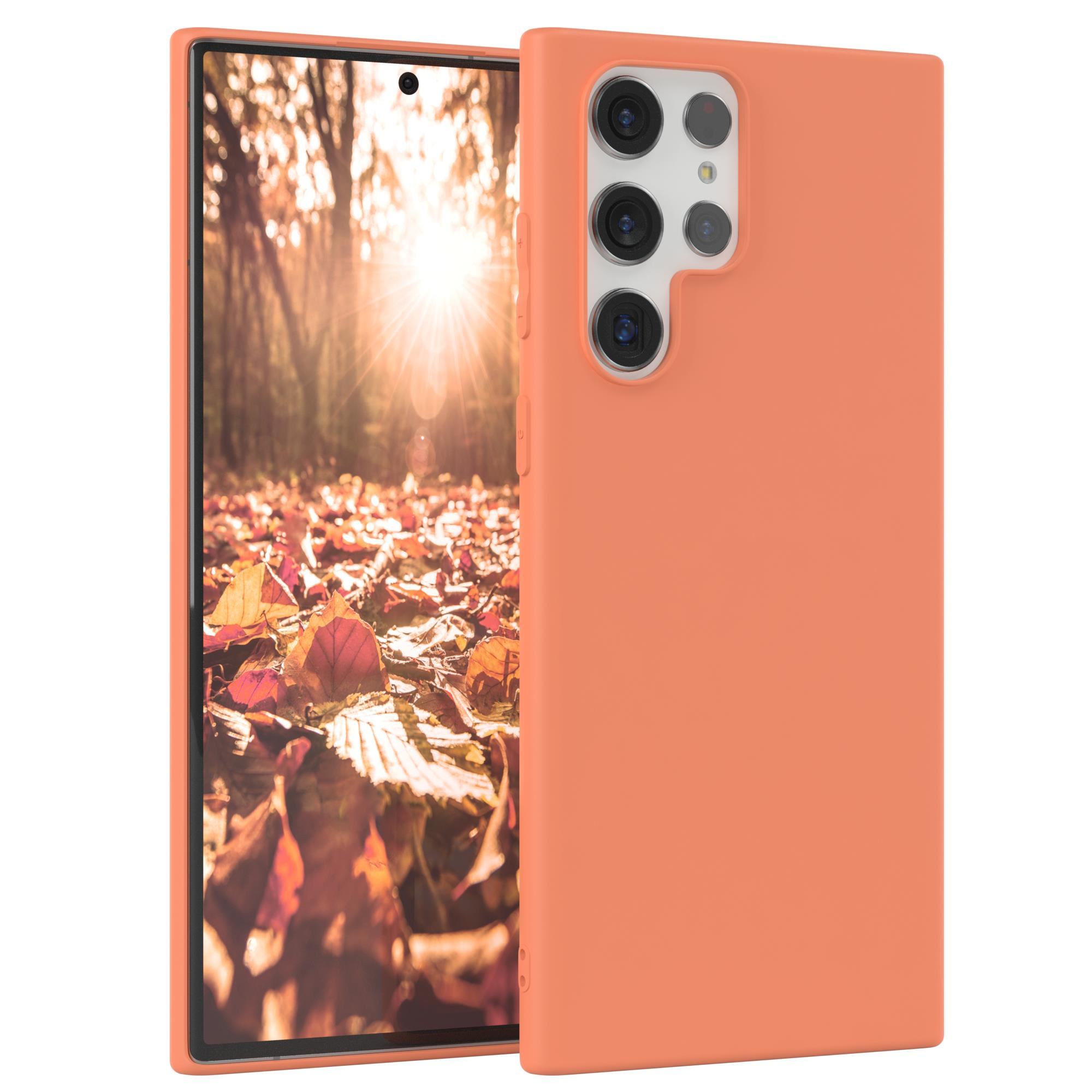 Ein Telefon in einer orangefarbenen Hülle mit Herbstlaub im Hintergrund.
