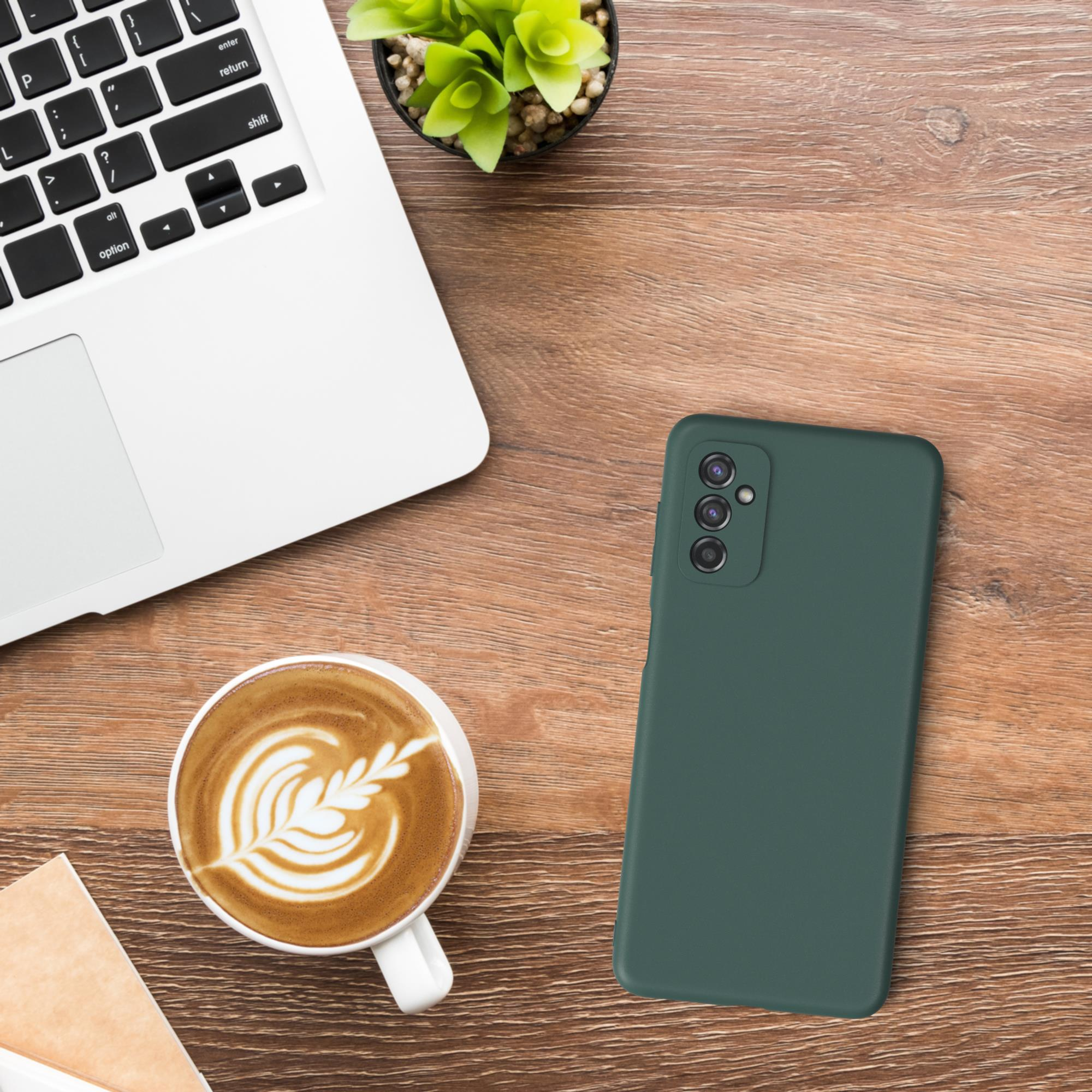 Eine grüne Handyhülle mit einem Laptop, einer Tasse Kaffee und einer Pflanze auf einem Holztisch. Die Handyhülle ist im Fokus.