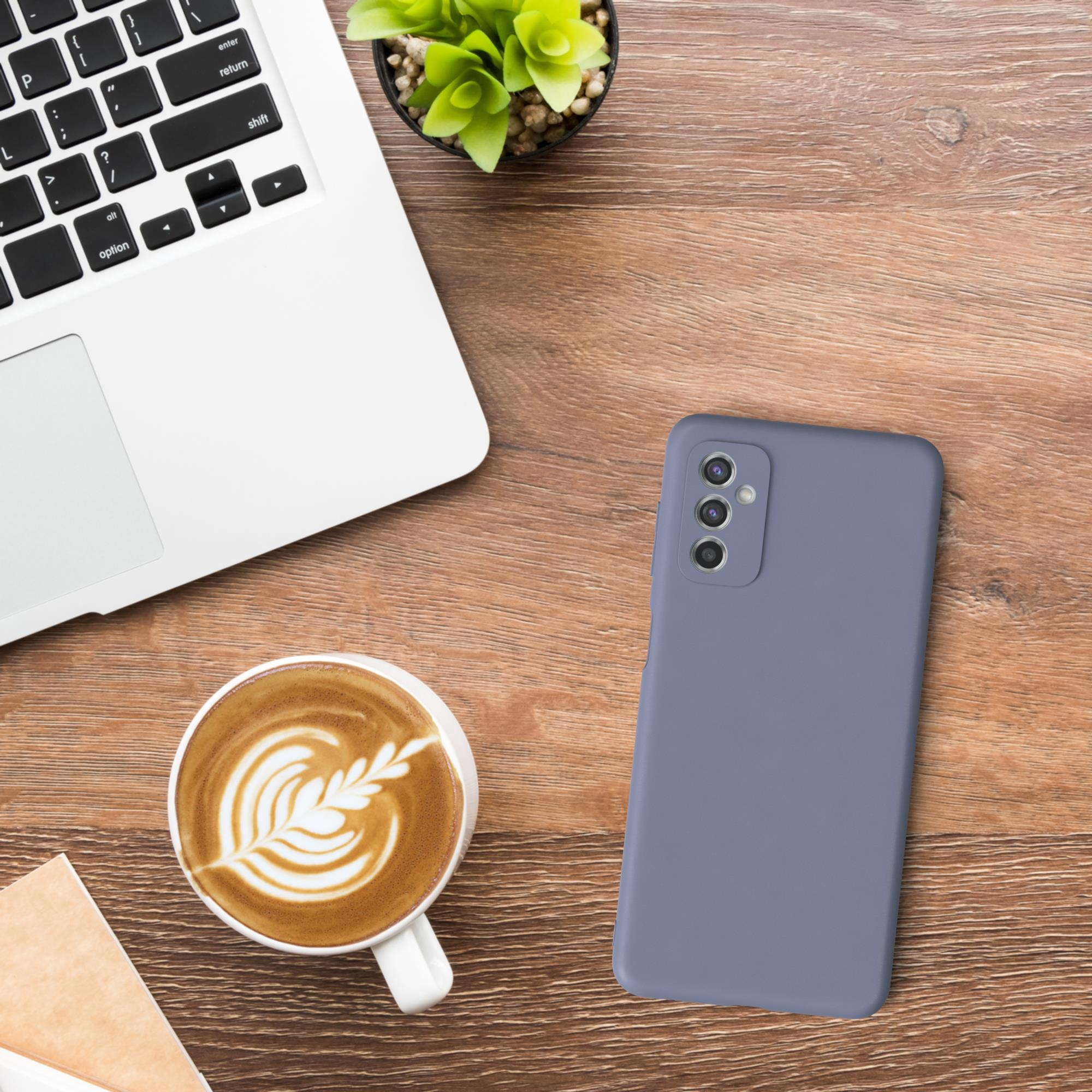 Ein Laptop, eine Tasse Kaffee und ein Telefon auf einem Holztisch. Das Telefon ist blau.
