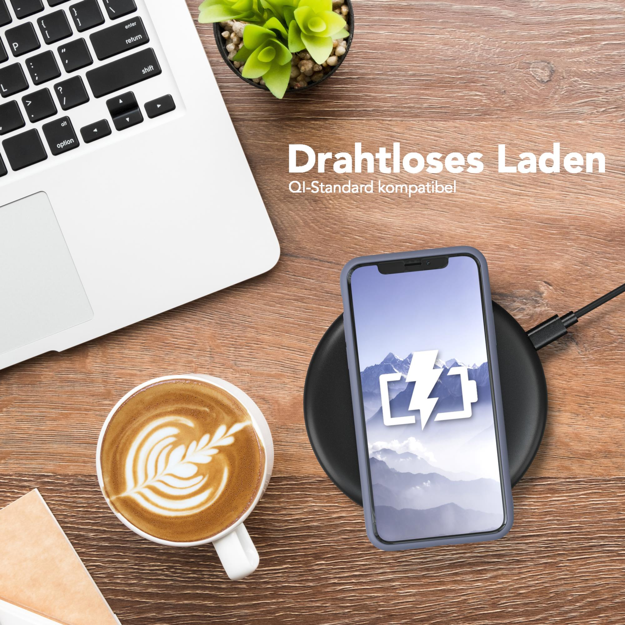 Ein Telefon auf einem kabellosen Ladegerät, neben einem Laptop und einer Kaffeetasse.
