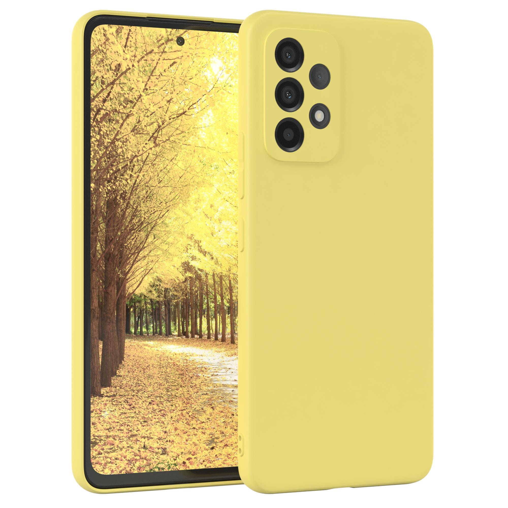 Gelbe Handyhülle mit dem Telefon darin. Das Telefon hat drei Kameras. Weißer Hintergrund.