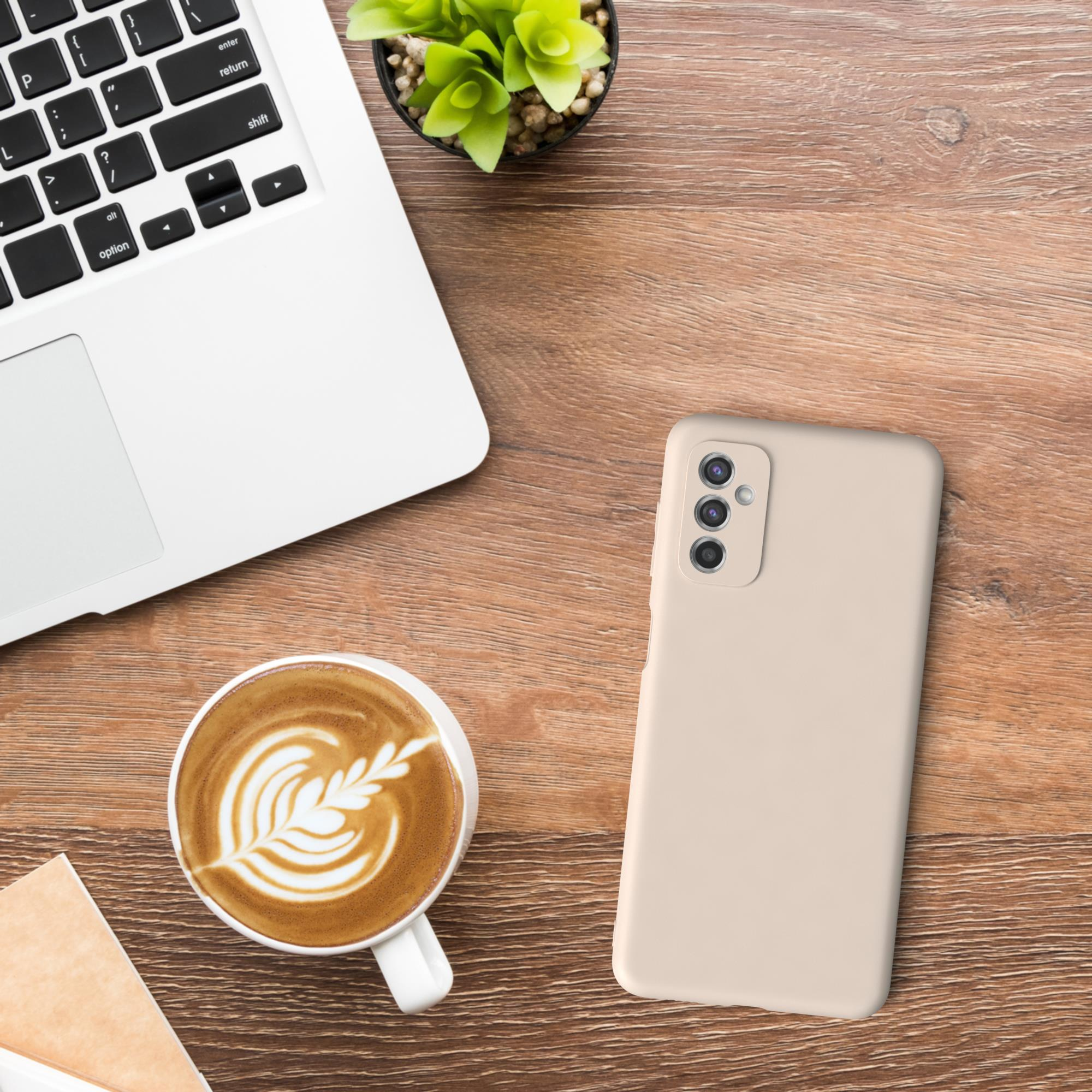 Laptop, Telefon, Kaffeetasse und kleine Pflanze auf einem Holztisch.