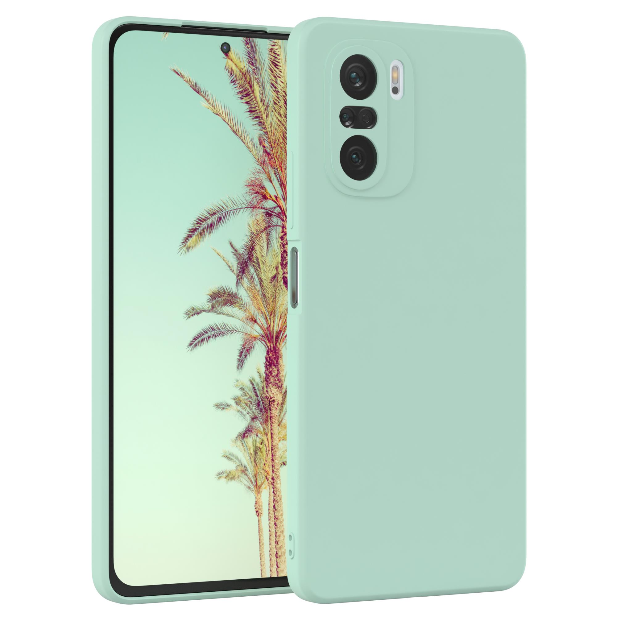 Minzgrüne Handyhülle mit Telefon. Zeigt Telefonkameras. Hintergrund ist ein Strand. Weißer Hintergrund.
