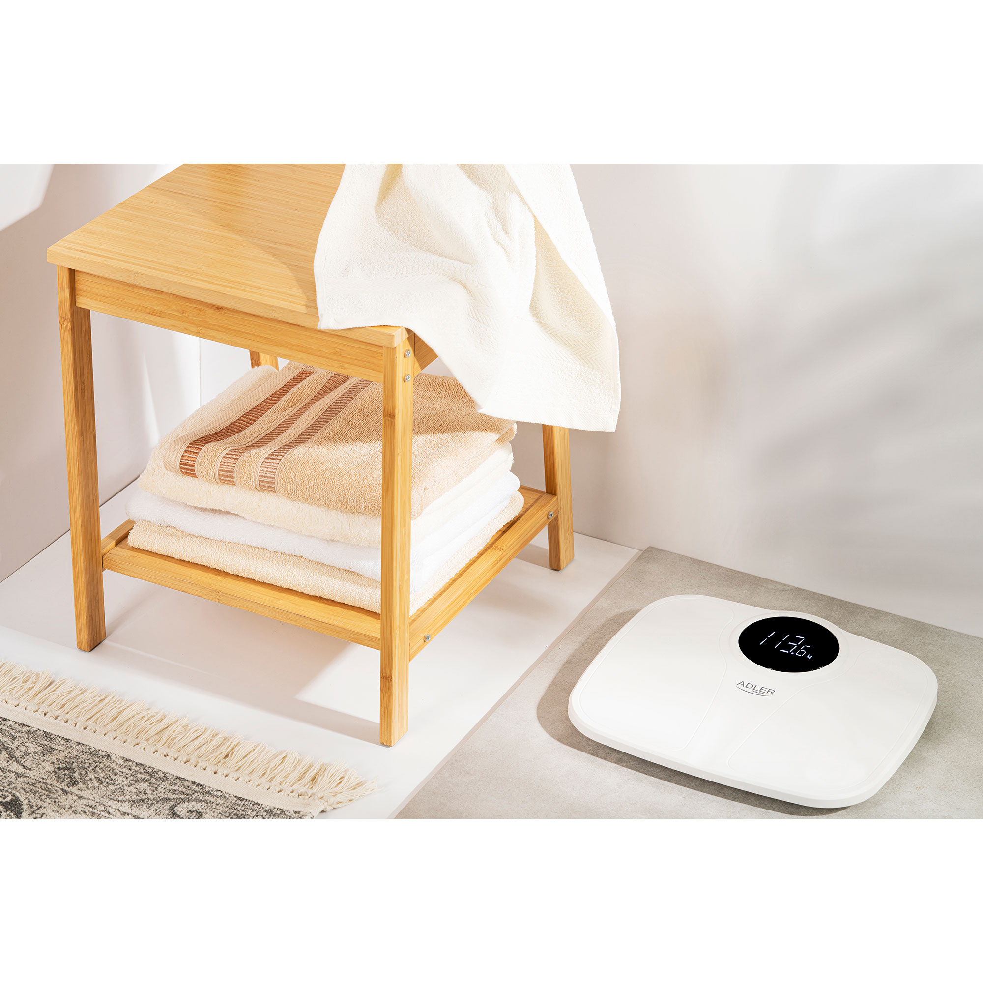Bambusowy stołek z ręcznikami, waga z wyświetlaczem wagi i dywan.