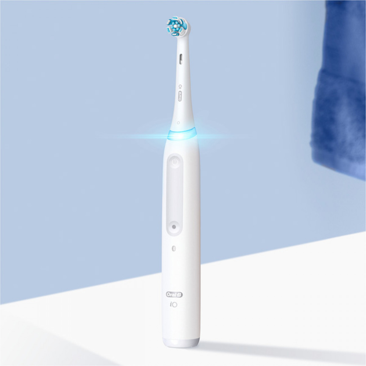 Spazzolino elettrico bianco su una superficie bianca, sfondo blu.