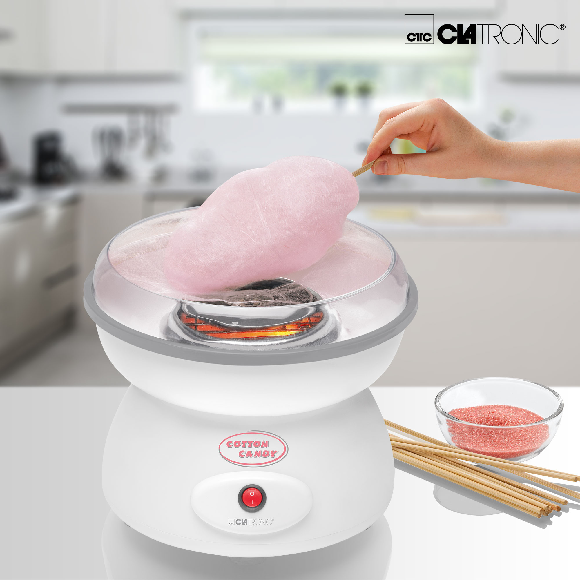 Persona haciendo algodón de azúcar con máquina y azúcar rosa.