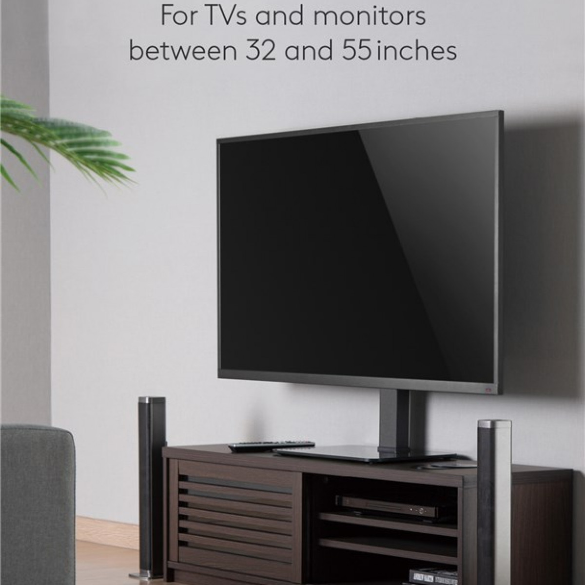 Fernseher auf einem Ständer mit Lautsprechern, auf einem dunkelbraunen Schrank, mit weißer Wand.