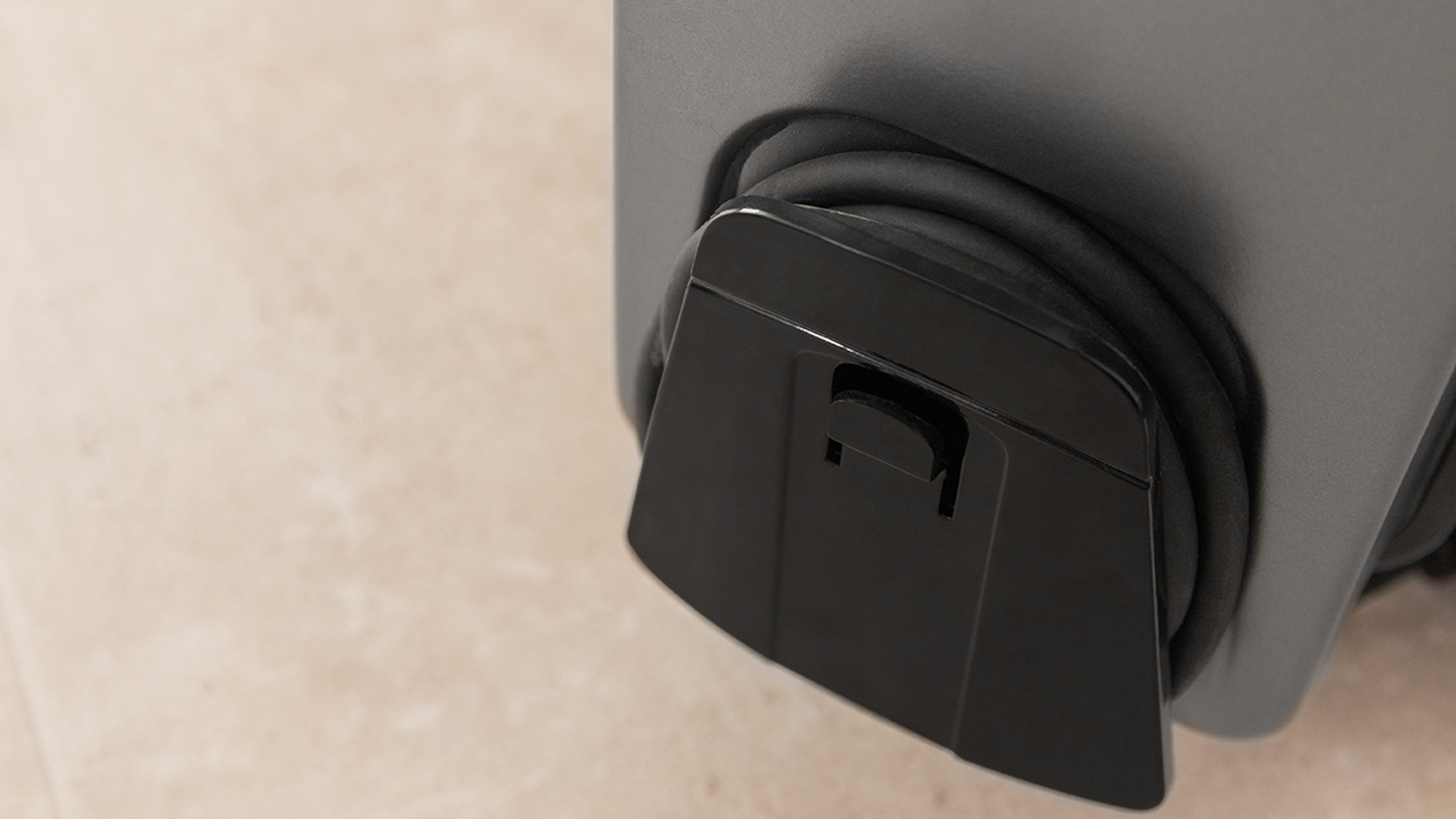 Czarna plastikowa osłona na szarej maszynie, z czarnym wężem.