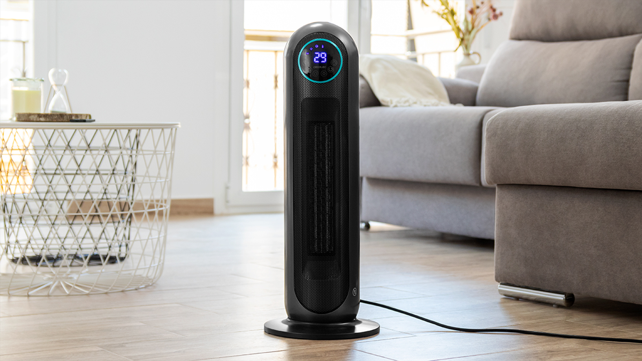 Czarny grzejnik wieżowy z wyświetlaczem cyfrowym. Stoi na okrągłej podstawie i jest w salonie.