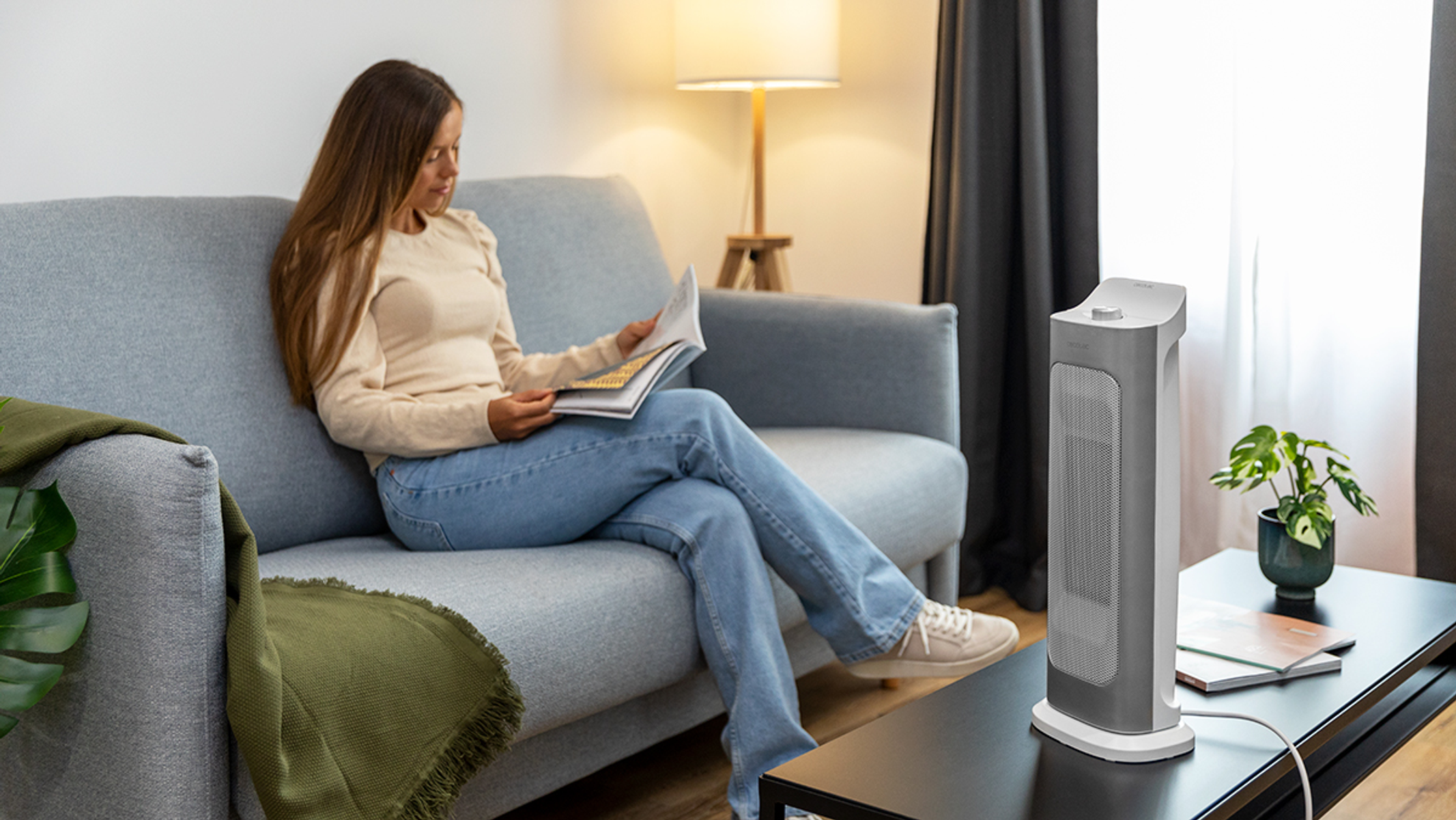 Kobieta siedzi na kanapie i czyta magazyn, z grzejnikiem z boku.