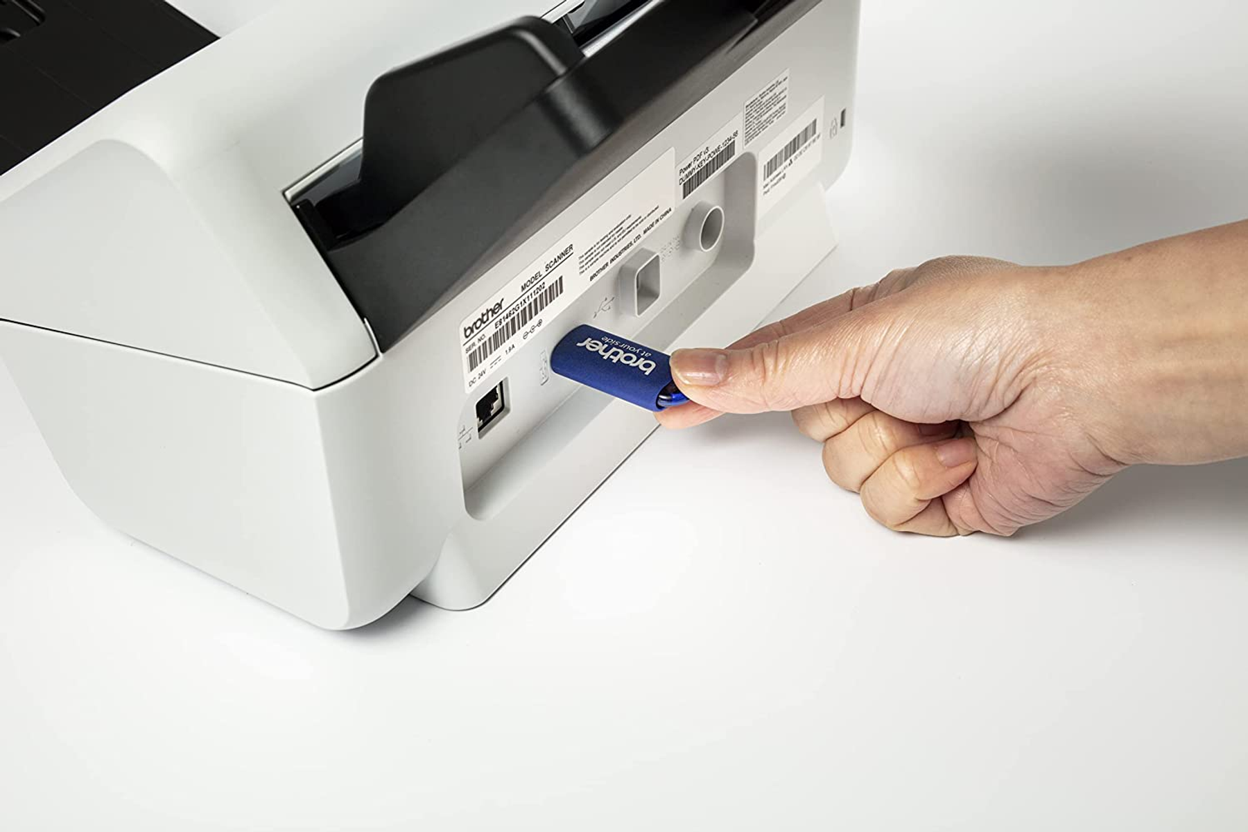 Dłoń wkładająca pendrive do drukarki.