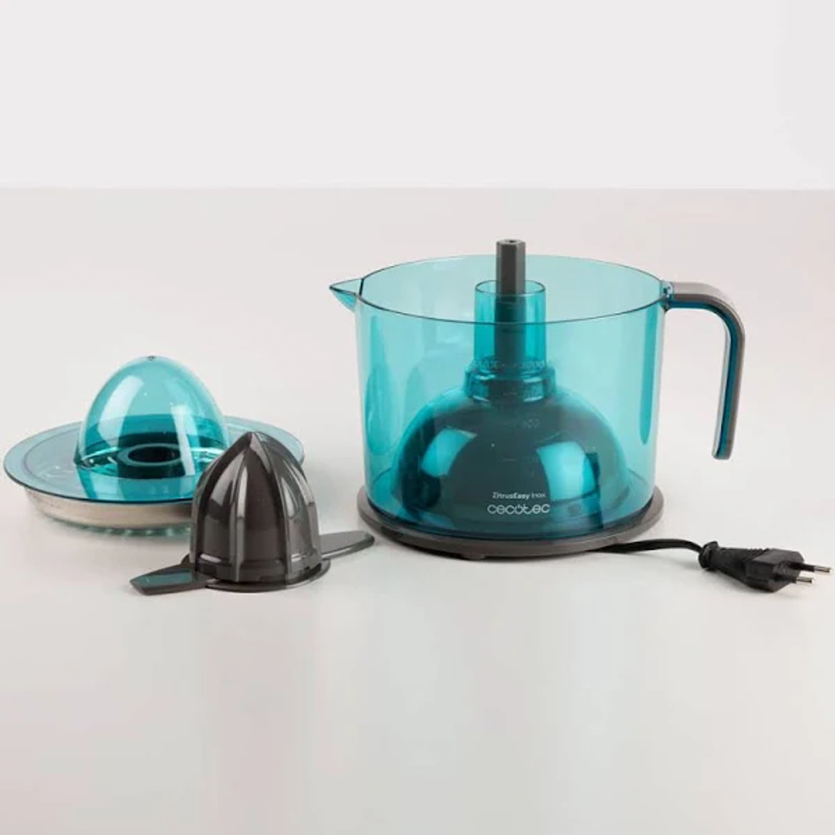 Exprimidor eléctrico turquesa con partes: tapa, cono y cable de alimentación negro.