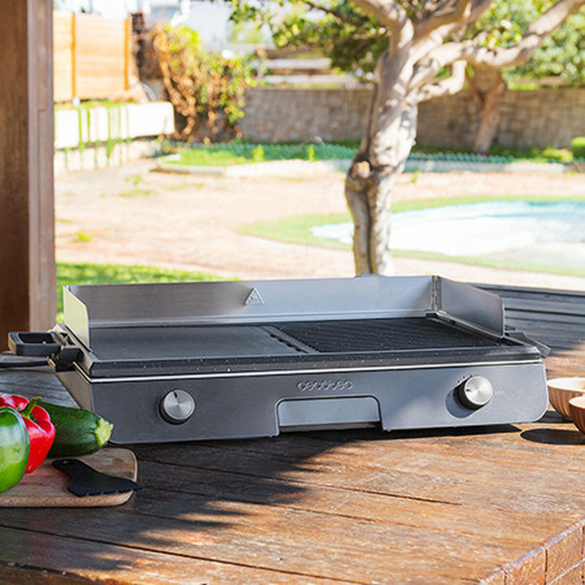 Parrilla al aire libre con verduras. La parrilla está sobre una mesa de madera con pimientos y calabacín.