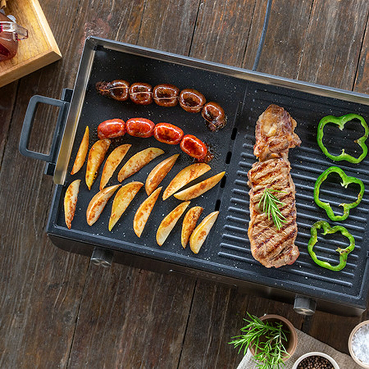 Parrilla con comida a la parrilla. Salchichas, patatas, bistec y pimientos en la parrilla.