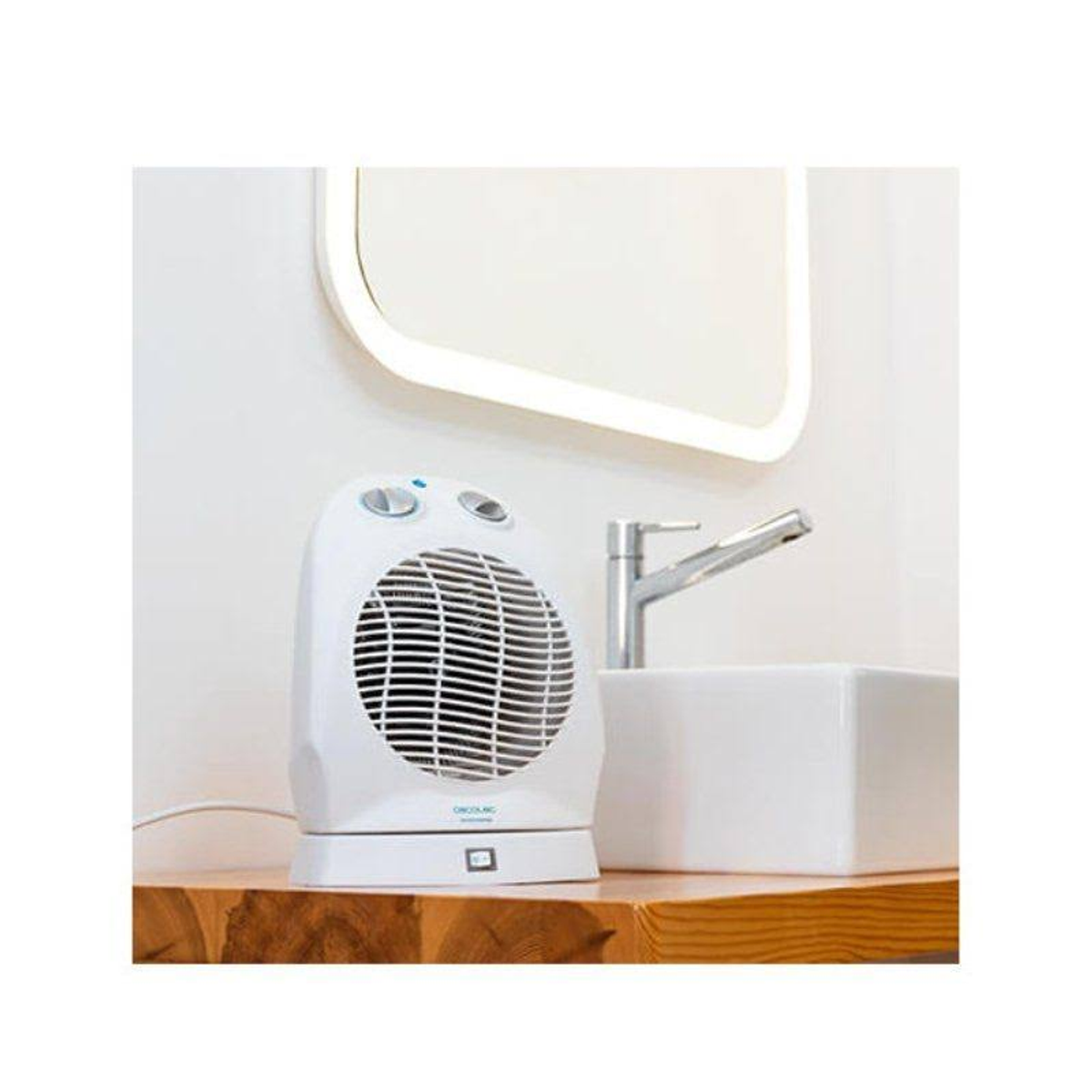 Biały grzejnik wentylatorowy do łazienki na drewnianej powierzchni, z lustrem i kranem w tle.