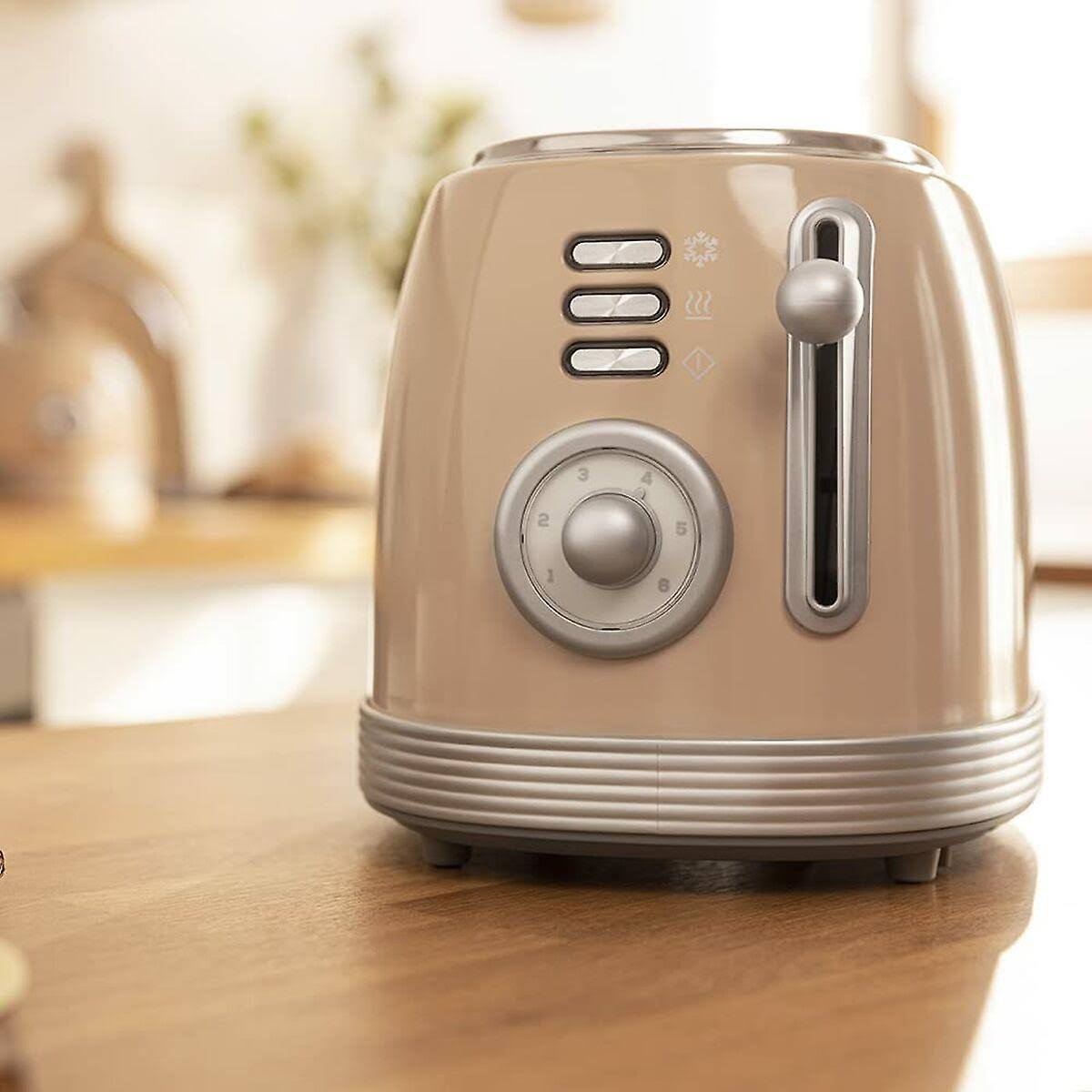 Ein beiger Toaster mit silbernen Akzenten, einem Drehknopf und Knöpfen. Er steht auf einer Holzoberfläche, mit unscharfem Hintergrund.
