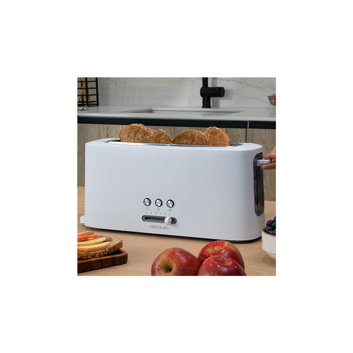 Biały toster z dwiema kromkami chleba, jabłkami i borówkami na drewnianym stole.