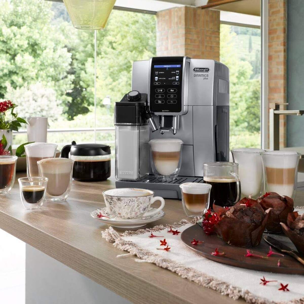 Srebrny ekspres do kawy z filiżankami i ciastkami na drewnianym blacie.