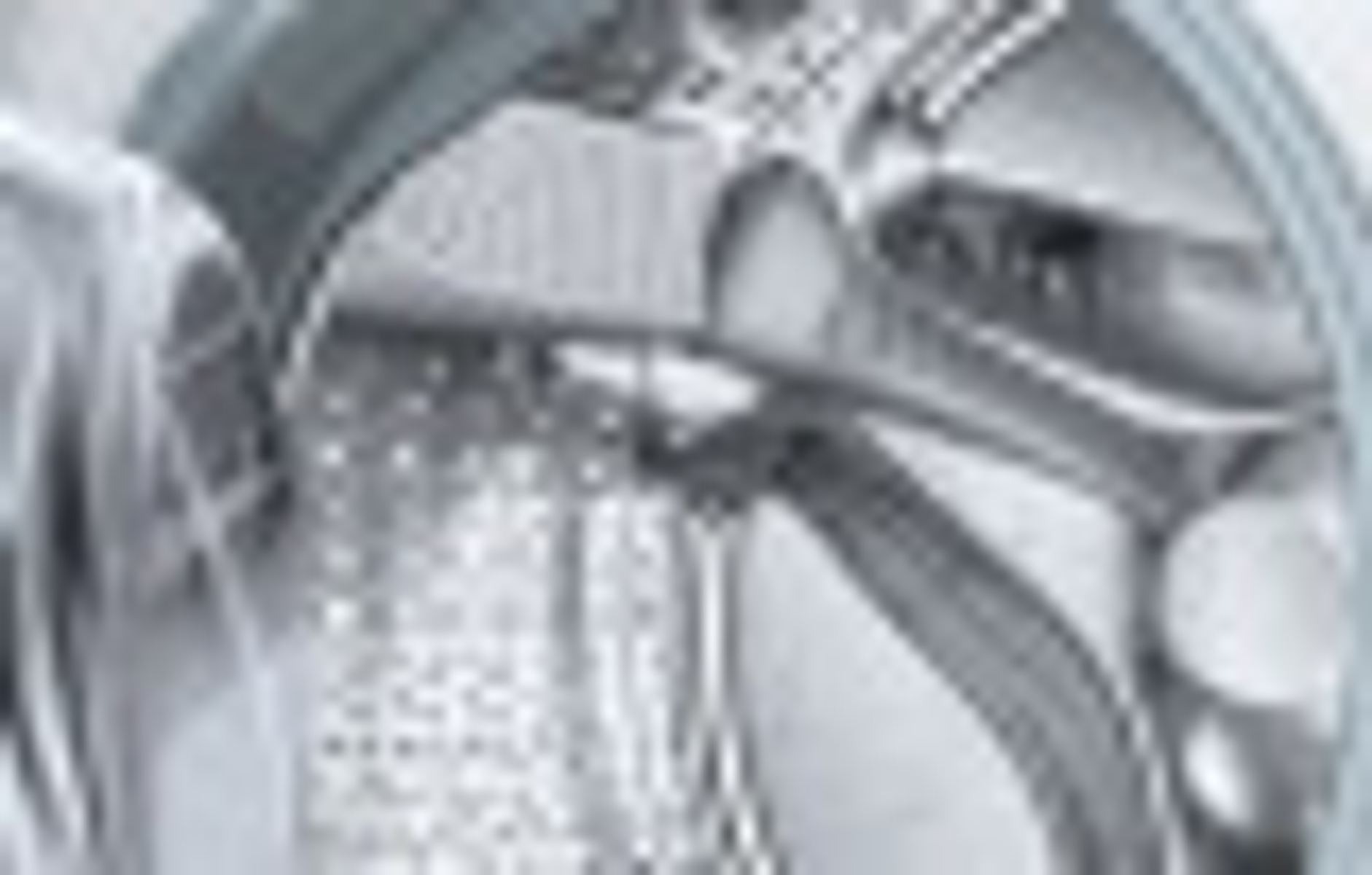 Wewnątrz pralki widoczny jest metalowy bęben z perforowanym wnętrzem i przezroczystymi drzwiami.