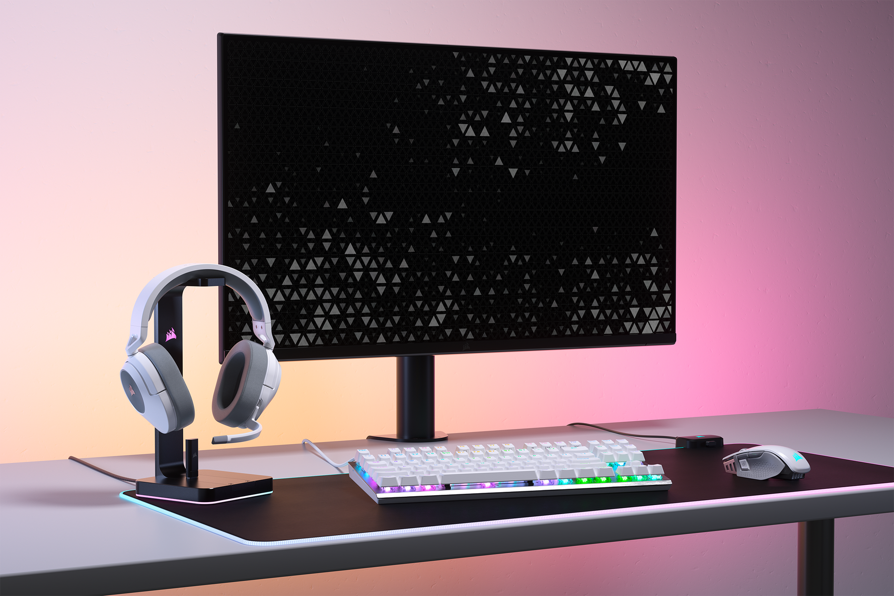 Konfiguracja do gier z monitorem, klawiaturą, myszą i słuchawkami. Tło jest różowo-pomarańczowe.