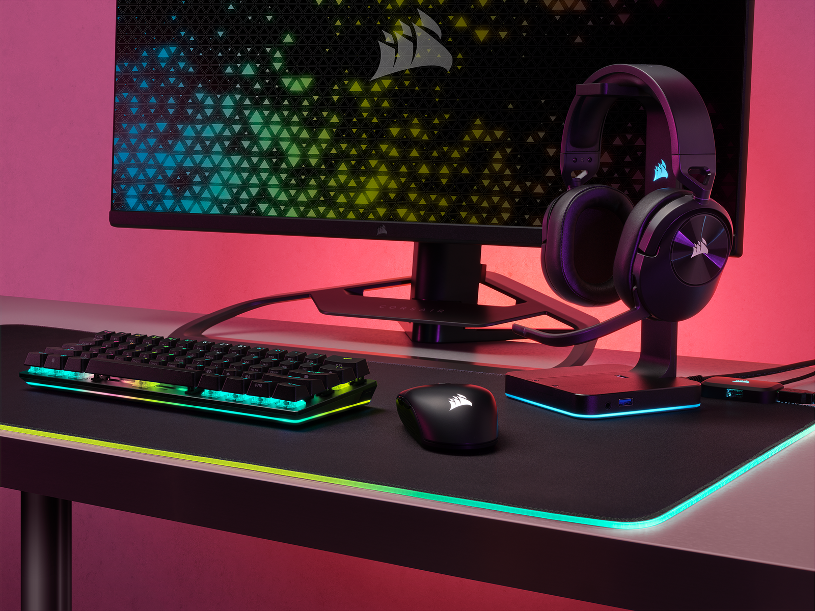 Configurazione di gioco: monitor, tastiera, mouse, cuffie. Nero e verde acqua, con illuminazione al neon. Sfondo sfocato.