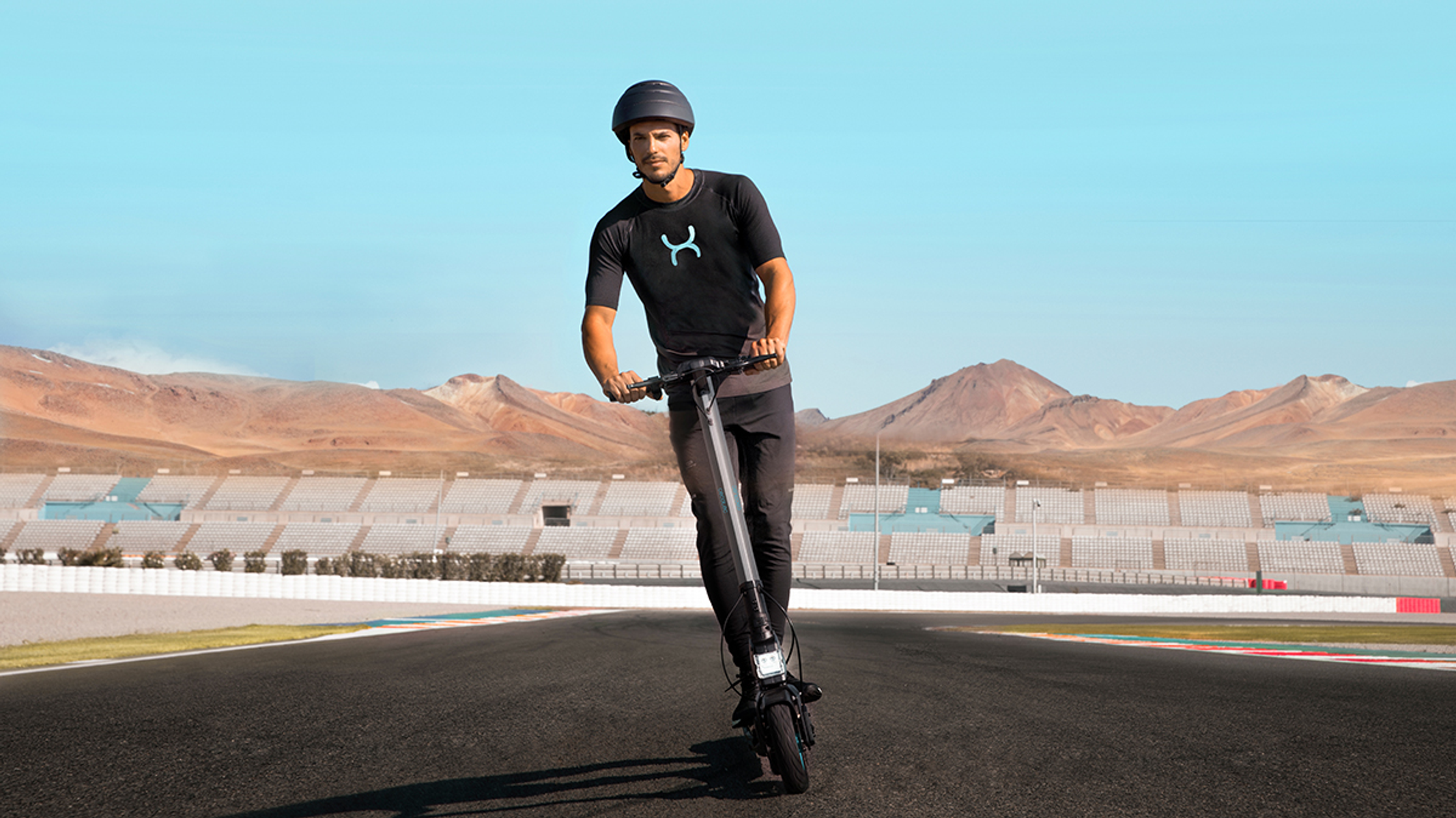 Un uomo su un monopattino elettrico su una pista, che indossa un casco.