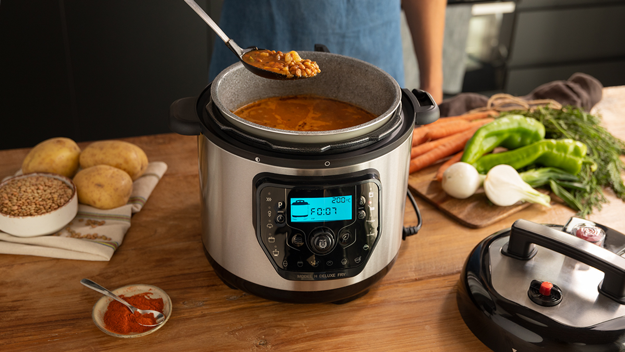 Olla a presión sobre una mesa con ingredientes y verduras.