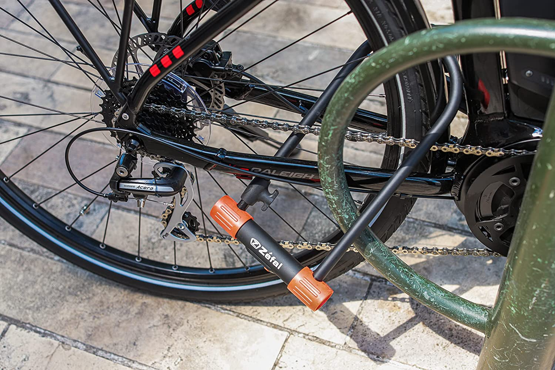 Fahrrad mit Schloss, das das Hinterrad an einem grünen Fahrradständer sichert.