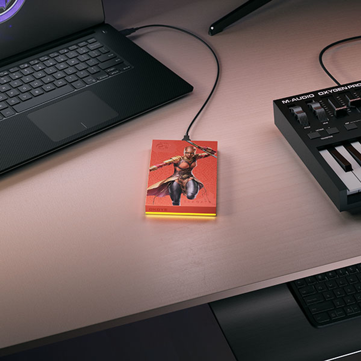 Czerwony zewnętrzny dysk twardy z wizerunkiem Czarnej Pantery podłączony do laptopa.