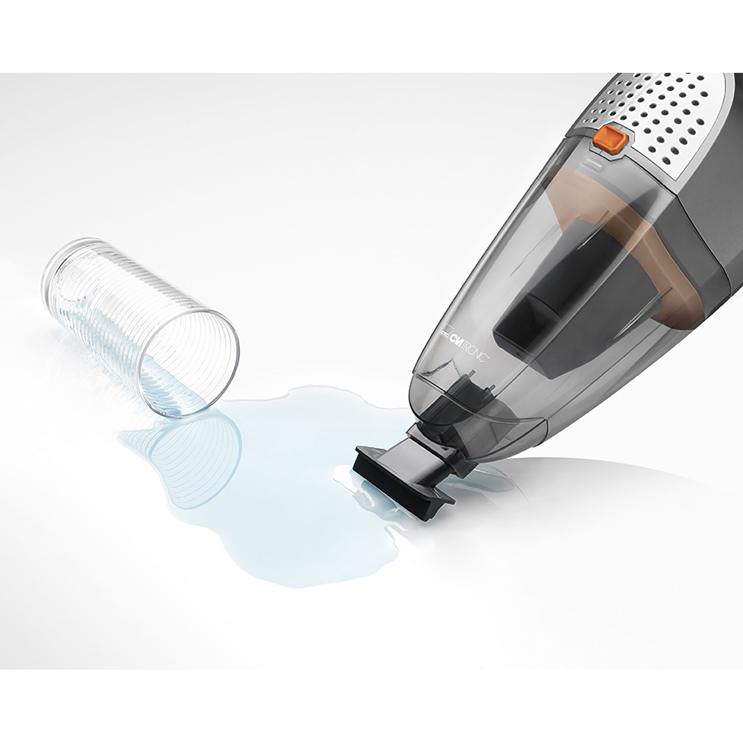 Szaro-czarny odkurzacz ręczny leży obok rozlanej wody na białej powierzchni.